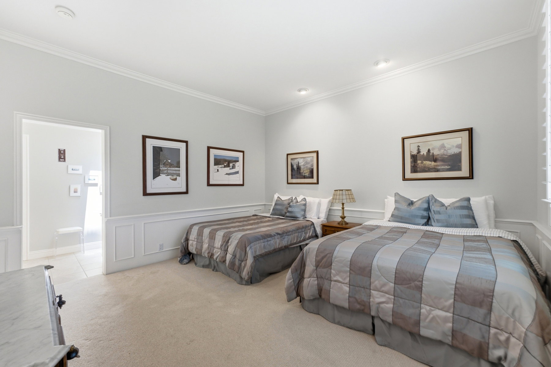 Spacious room featuring neutral carpeting, elegant crown molding, recessed lighting, wainscoting, and a white trim baseboard