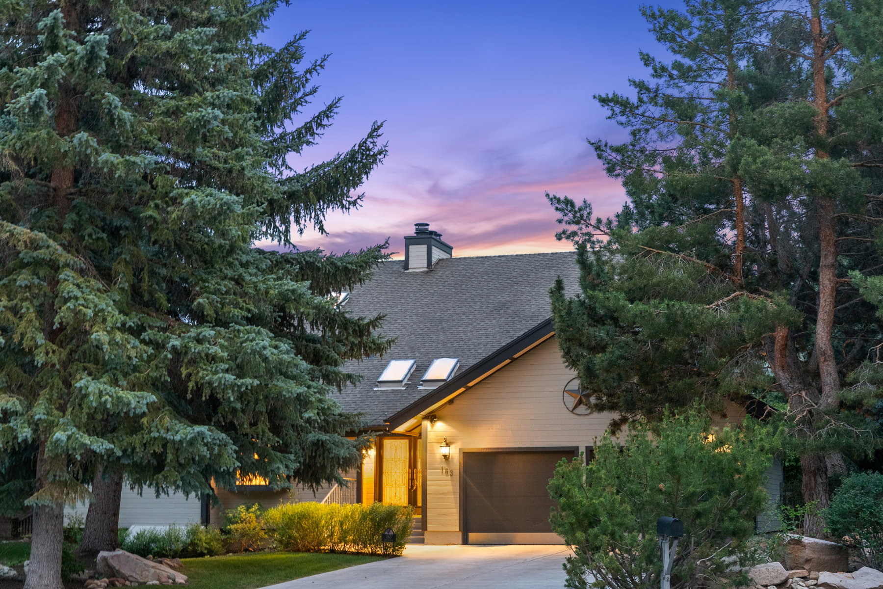 Gabled roofline residence featuring light-toned siding and a black garage door