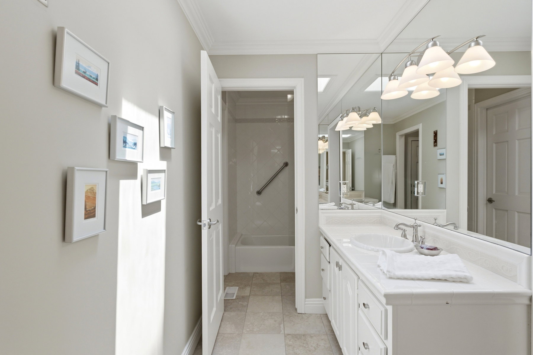 Double vanity with white cabinetry, integrated sinks, chrome faucets, and an expansive mirror