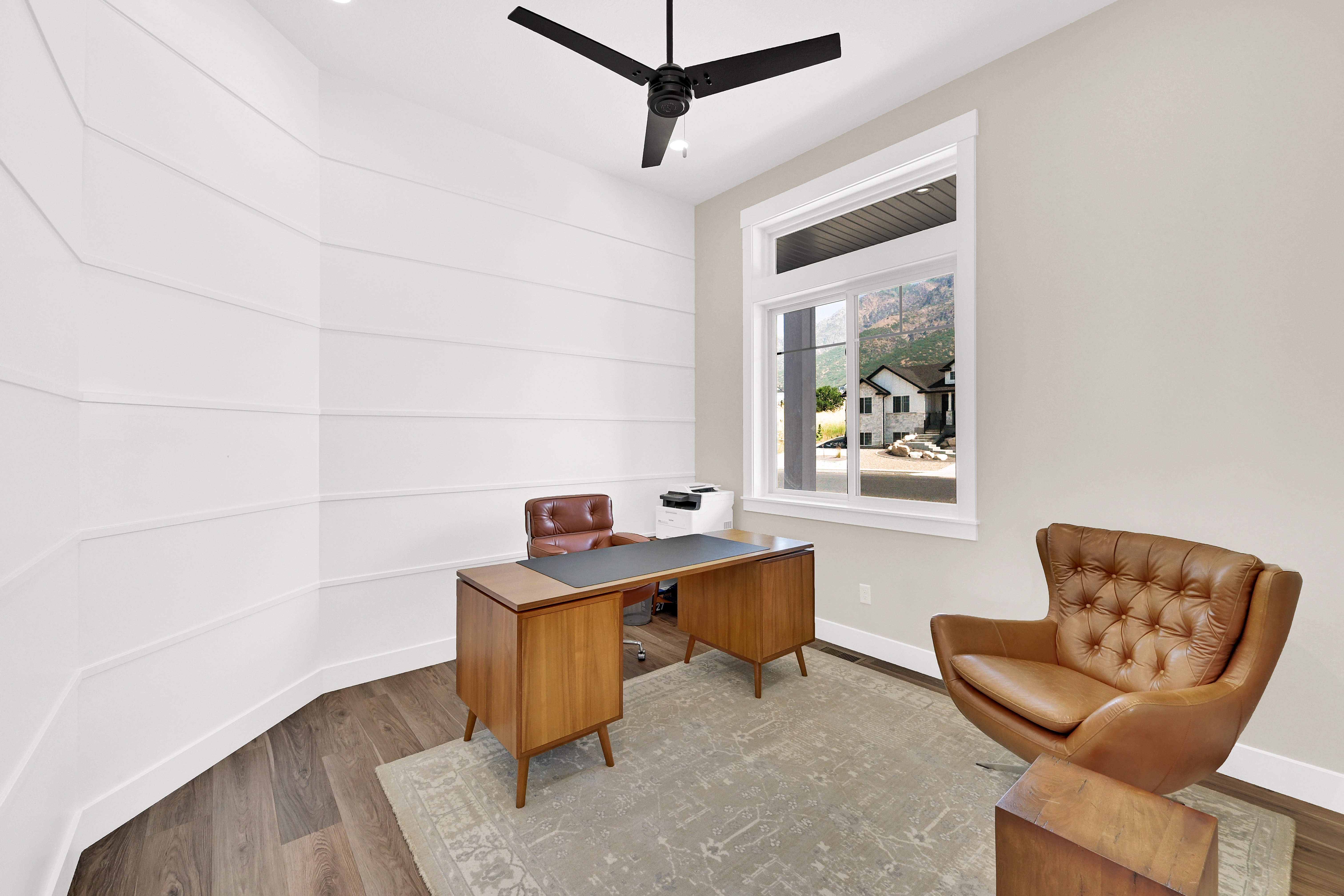 Interior room featuring horizontal wall paneling, a large window with white trim, and wood-finish flooring