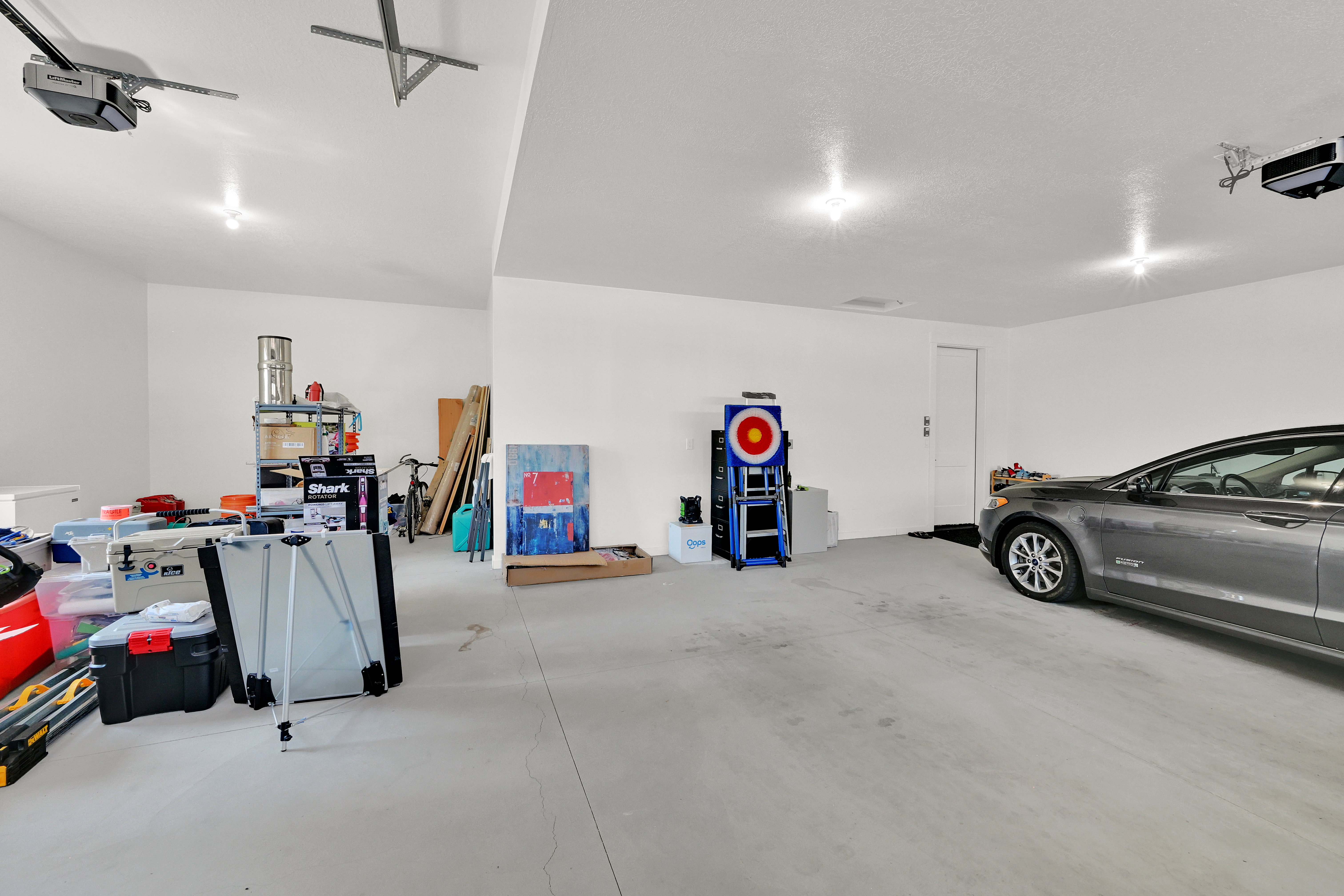 Spacious garage featuring a concrete floor, bright overhead lighting, and two automatic garage door openers