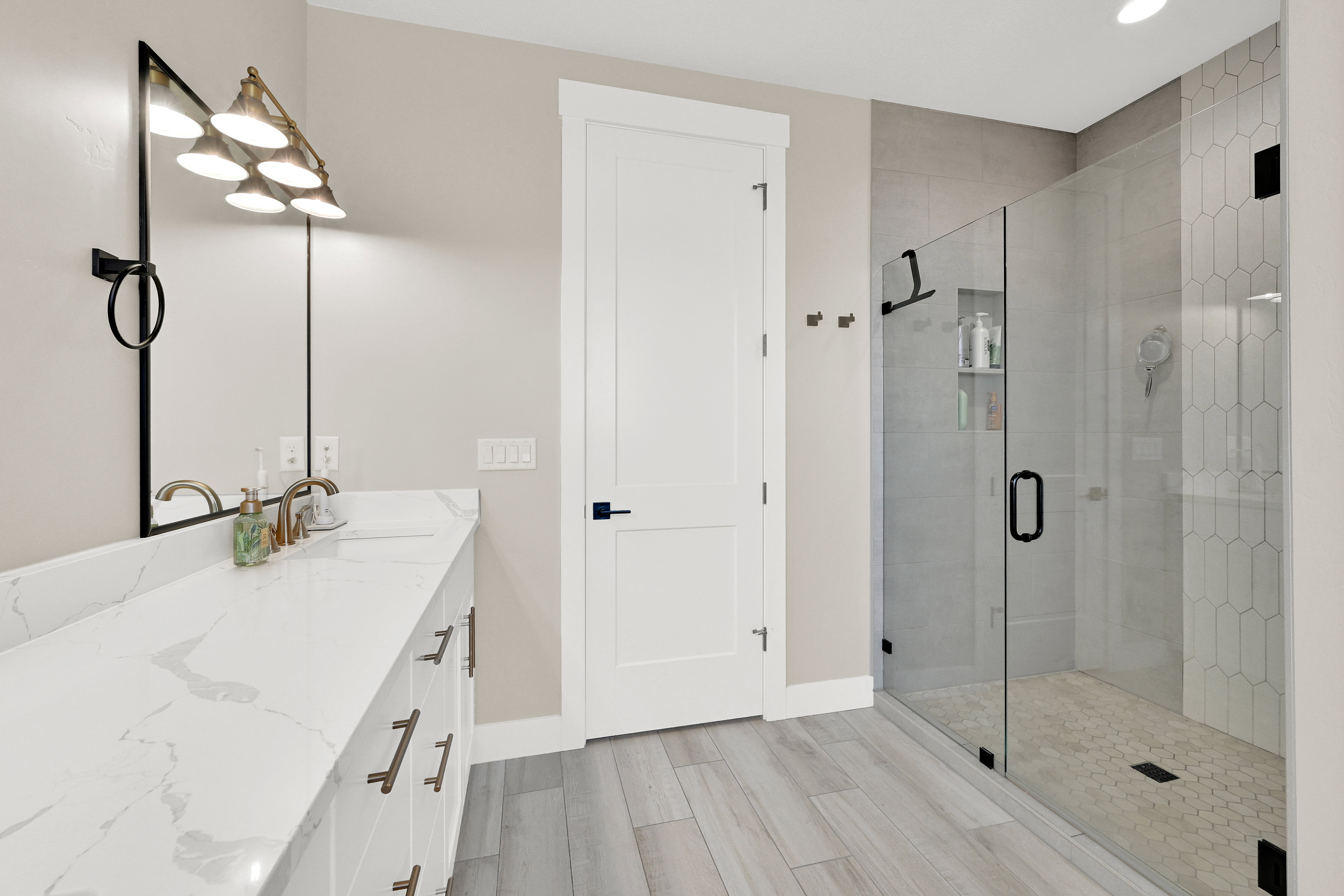Bathroom featuring an extended double vanity with integrated sinks and a glass-enclosed shower