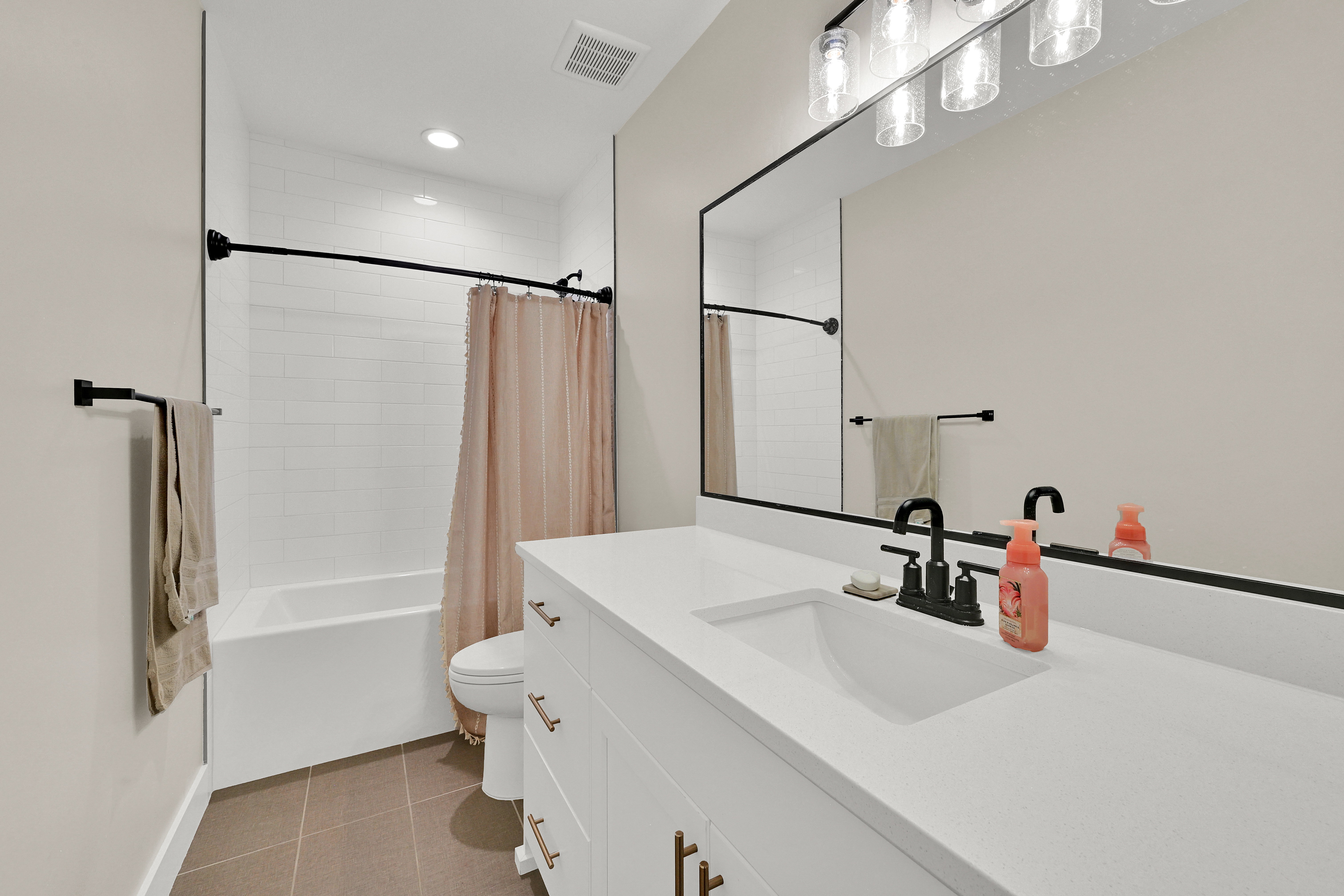 Bathroom featuring a white subway tile shower surround, a built-in tub, and matte black fixtures