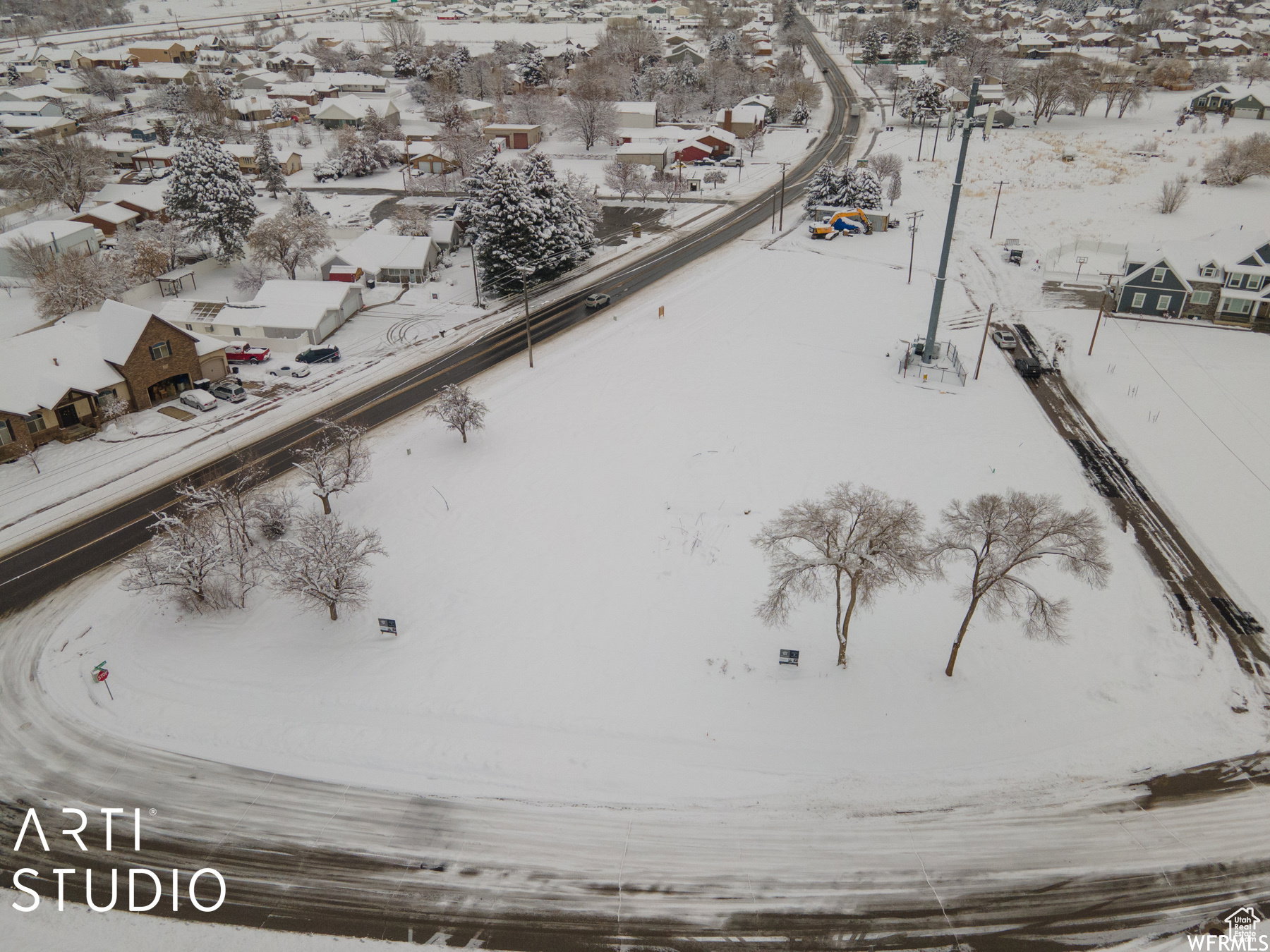 Expansive snow-covered land parcel, featuring mature trees and a curved road frontage