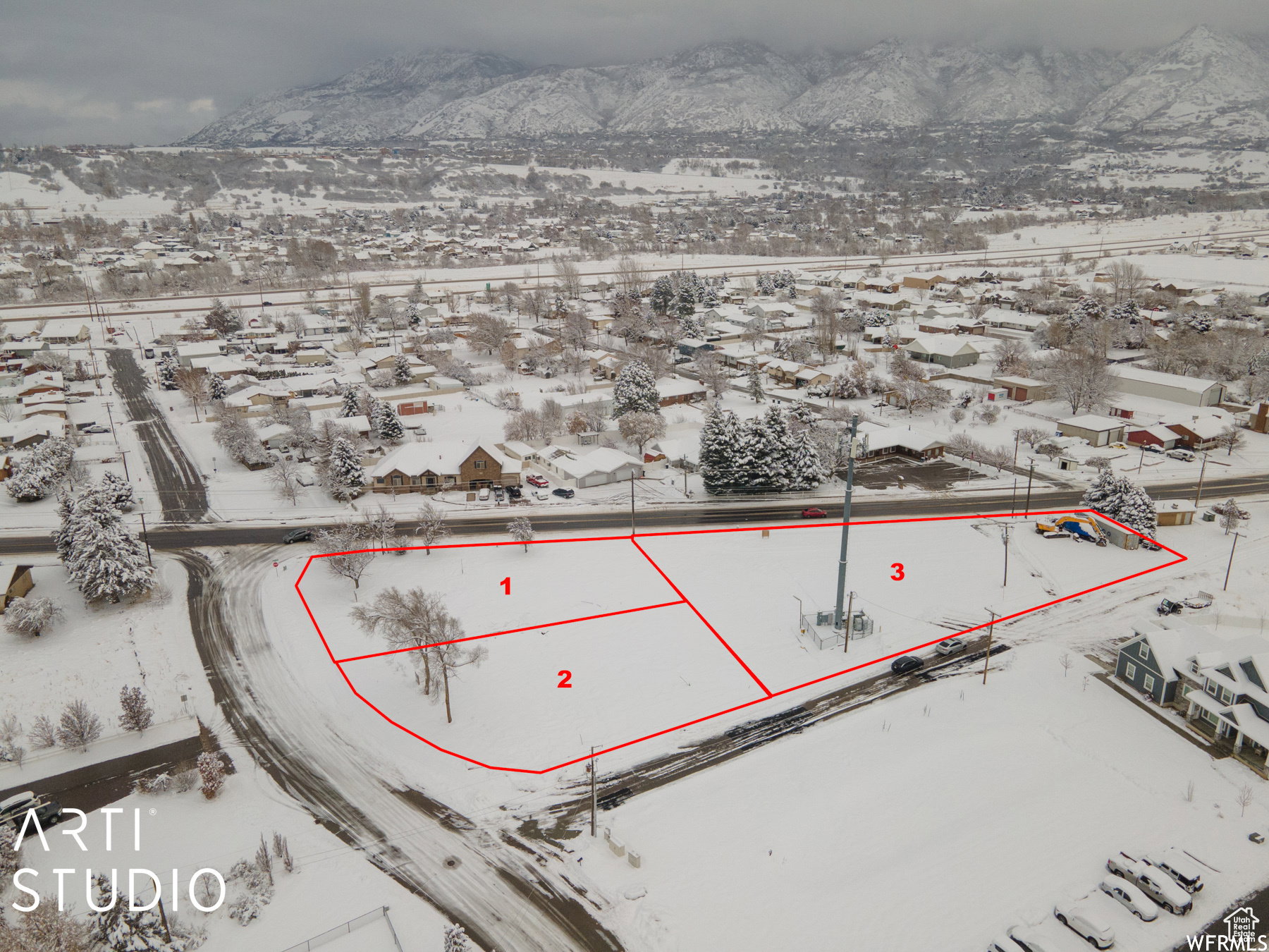 Aerial view of a snow-covered land parcel, featuring defined plot lines and proximity to a paved road
