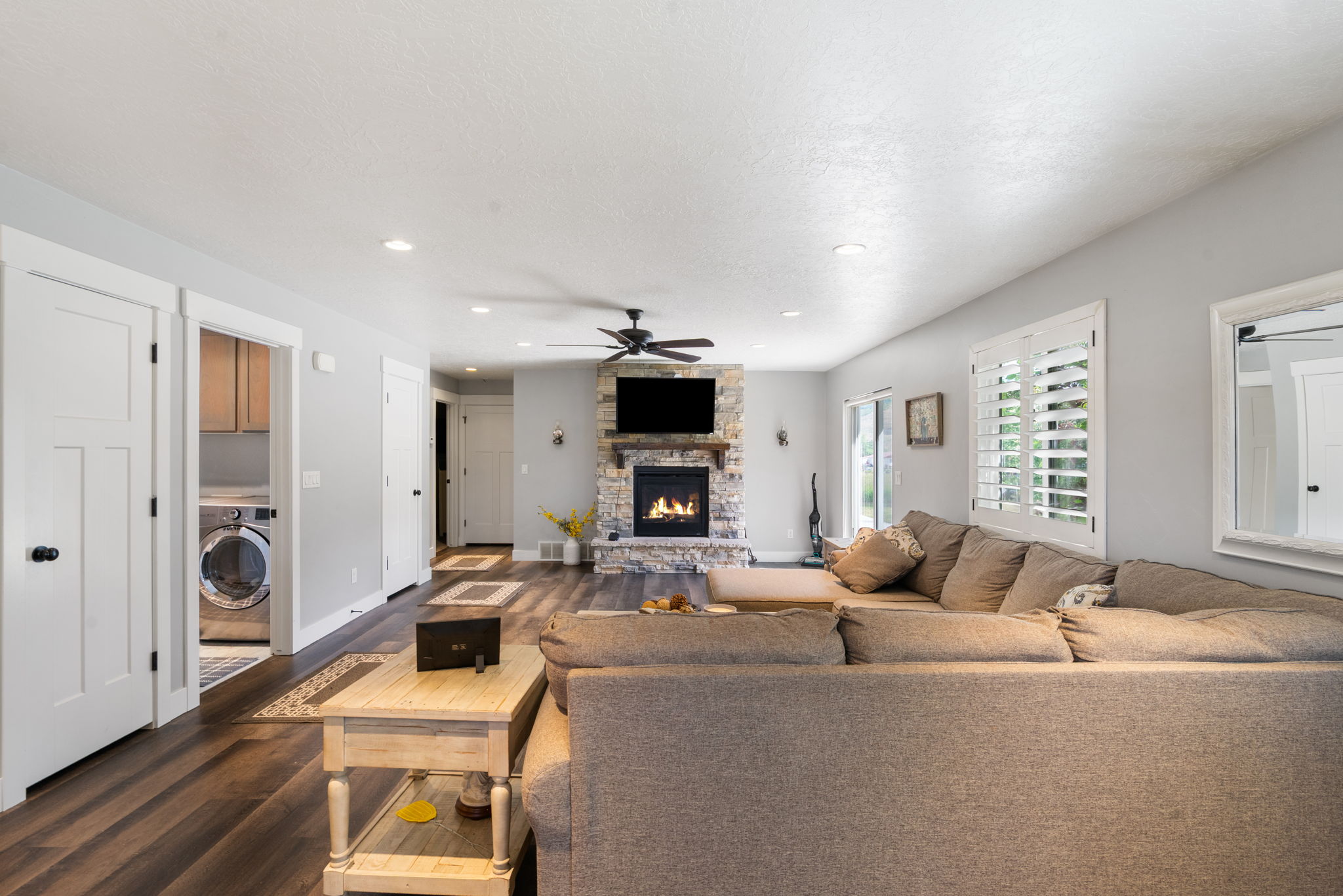 Living area featuring a stone-clad fireplace, wood-finish flooring, recessed lighting, and a ceiling fan
