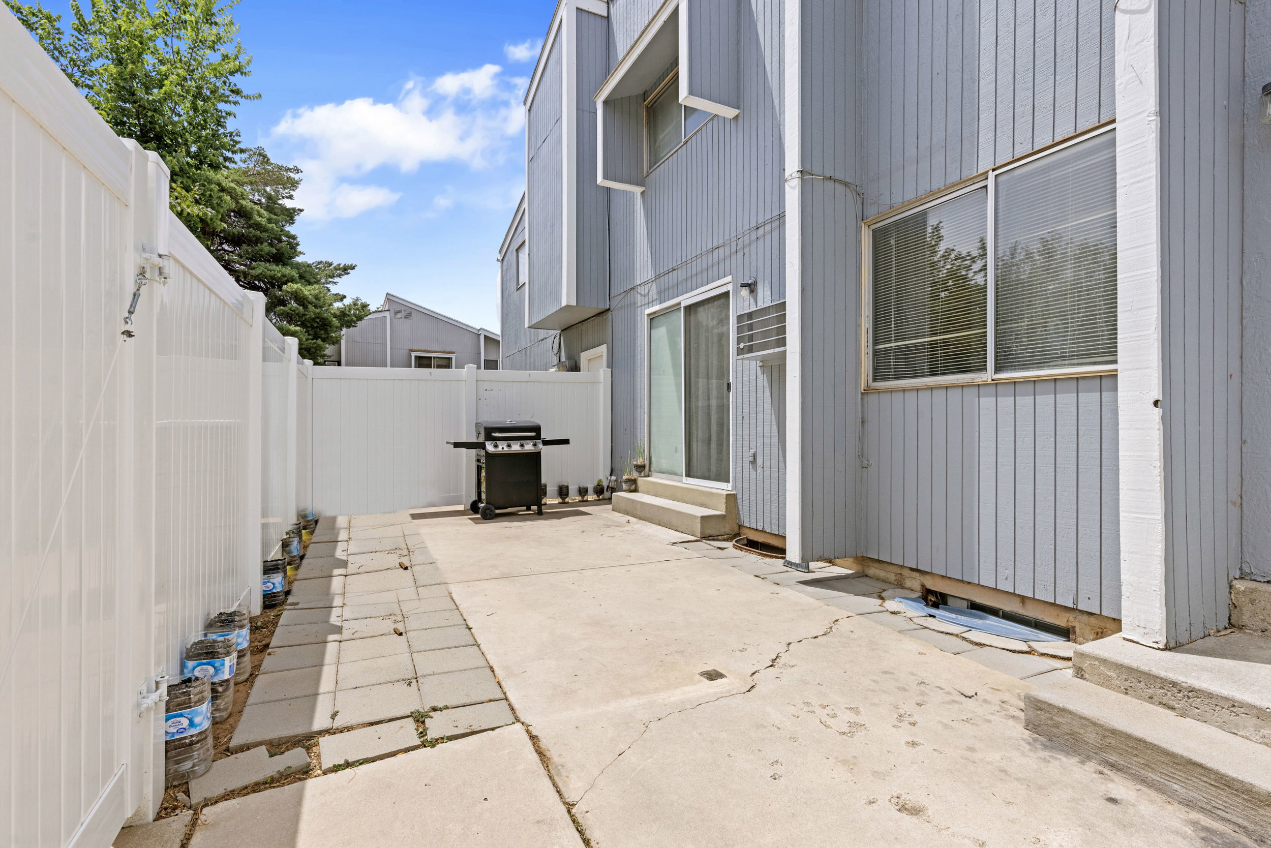 Private patio area featuring a concrete slab and surrounding white fencing