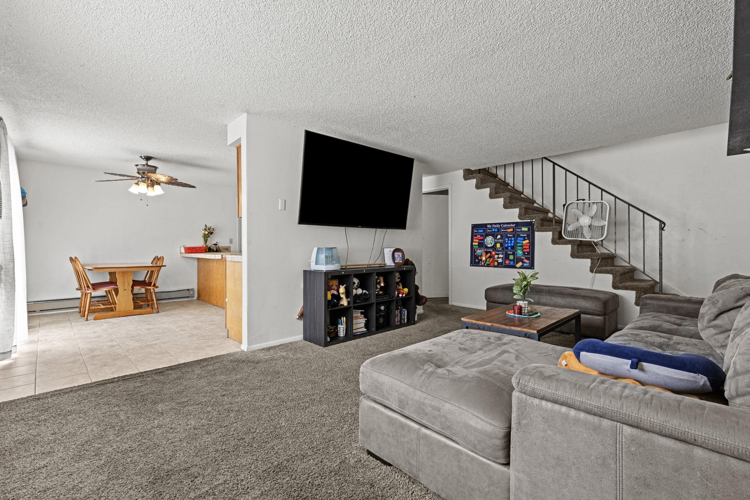 Carpeted living area with a staircase featuring a metal railing