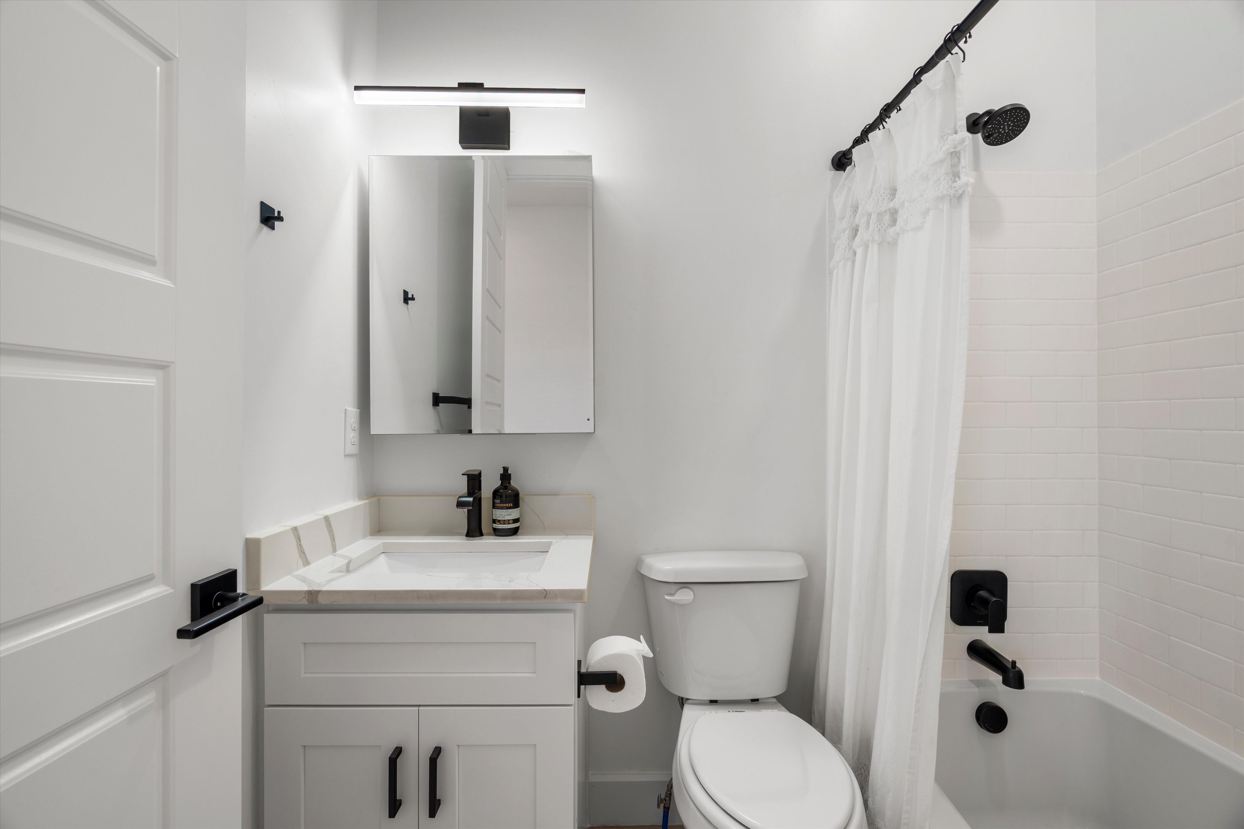 Bathroom featuring a white subway tile surround, matte black shower fixtures, and a curved shower rod