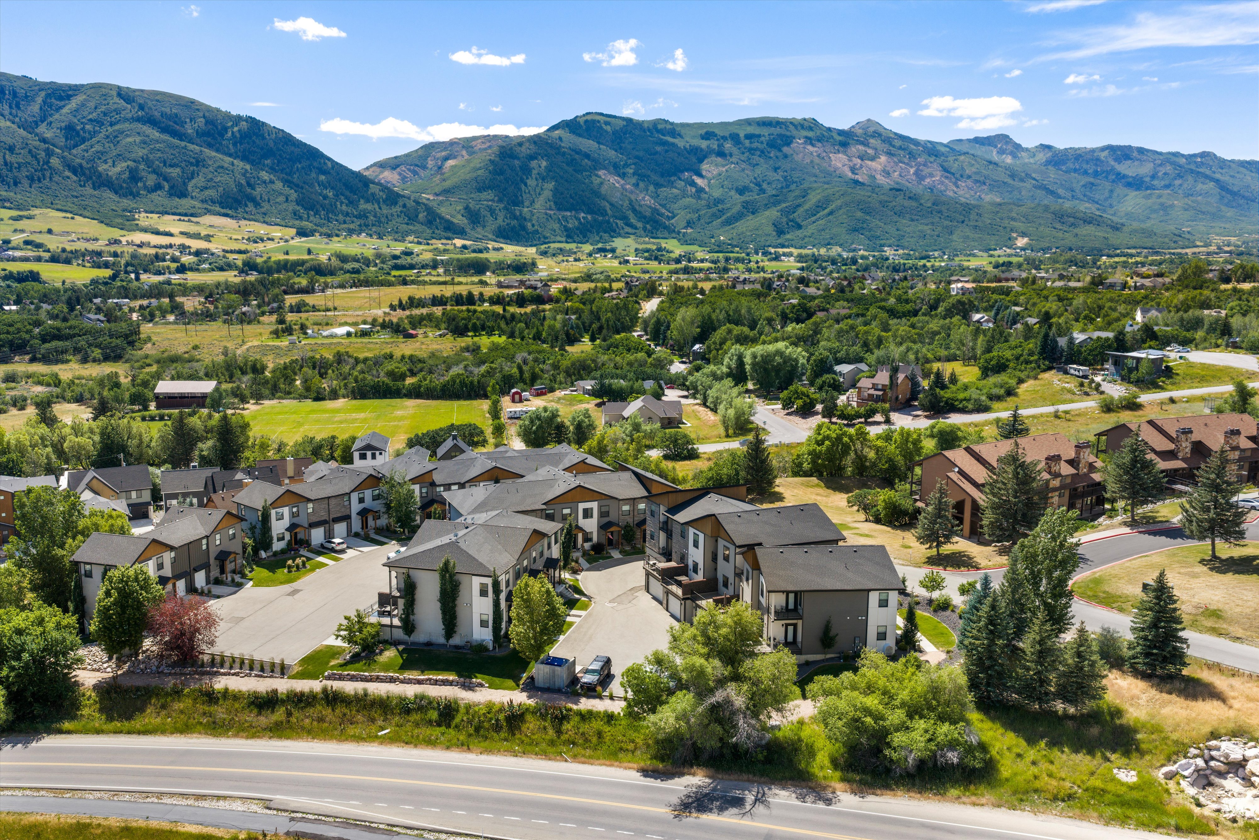 Modern community with contemporary architecture and extensive landscaping, surrounded by expansive green spaces and mountainous terrain