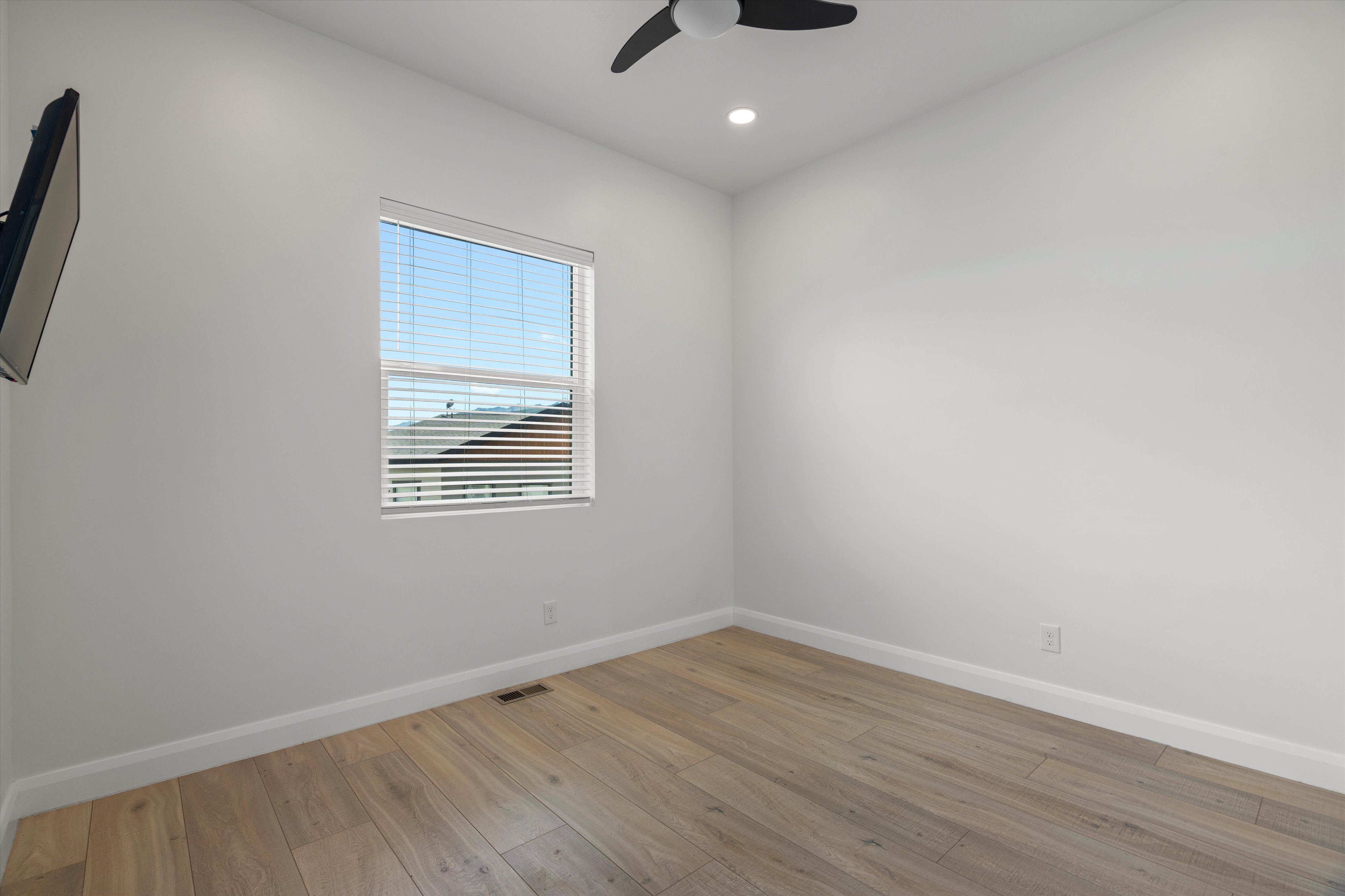 Spacious room featuring wood-finish flooring, white baseboards, and bright white walls