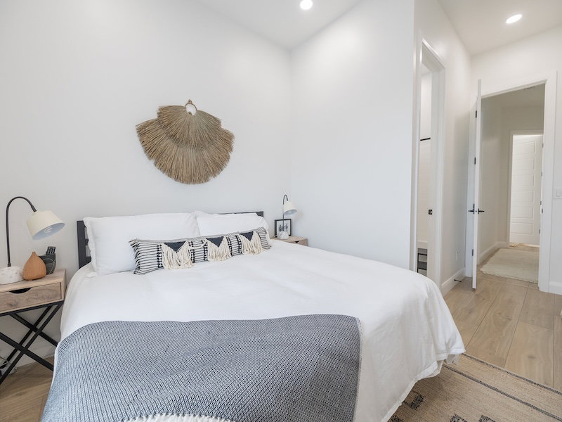Bright bedroom featuring recessed lighting, light wood-finish flooring, white walls, and a black metal bed frame