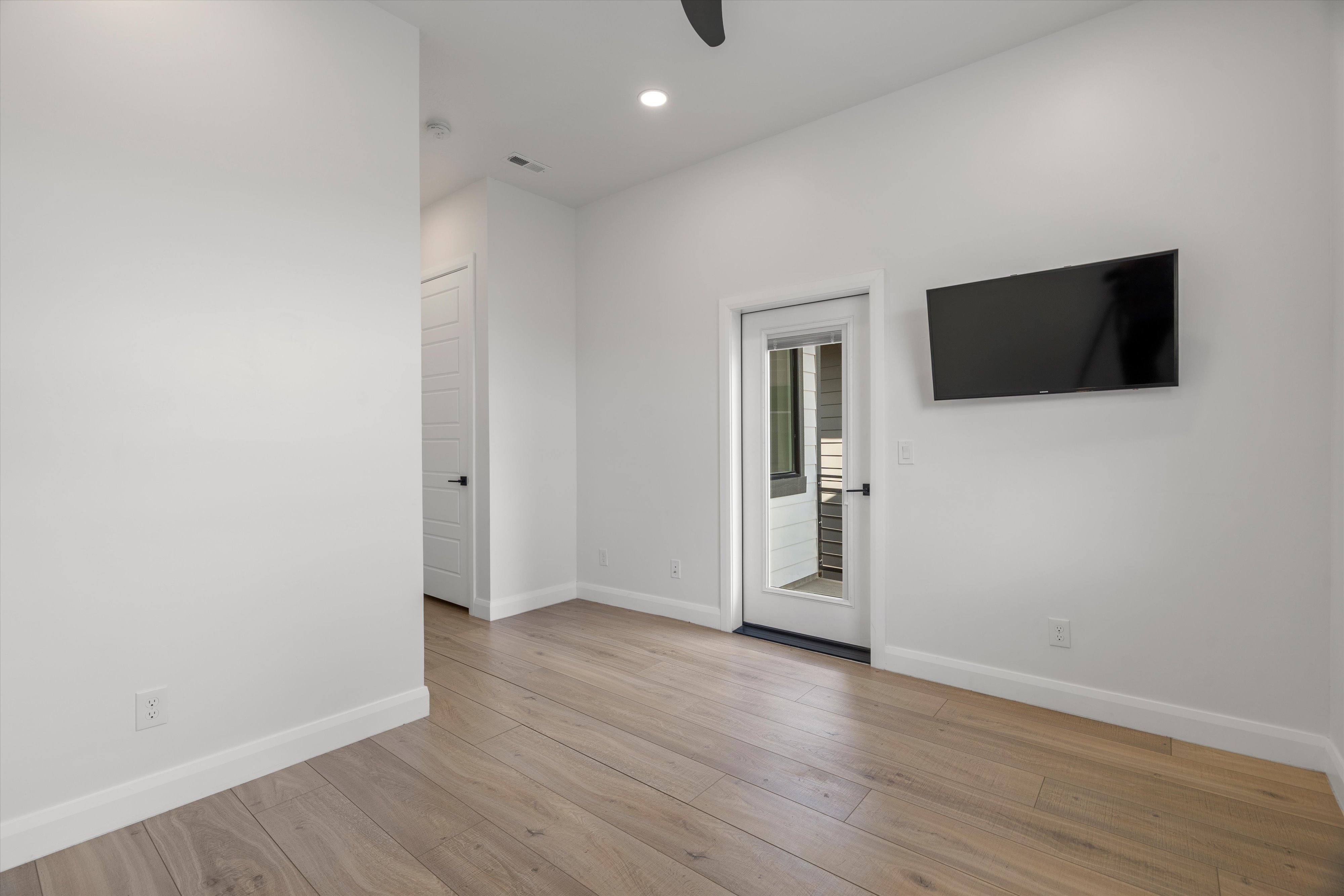 Light wood-finish flooring with white baseboards and walls