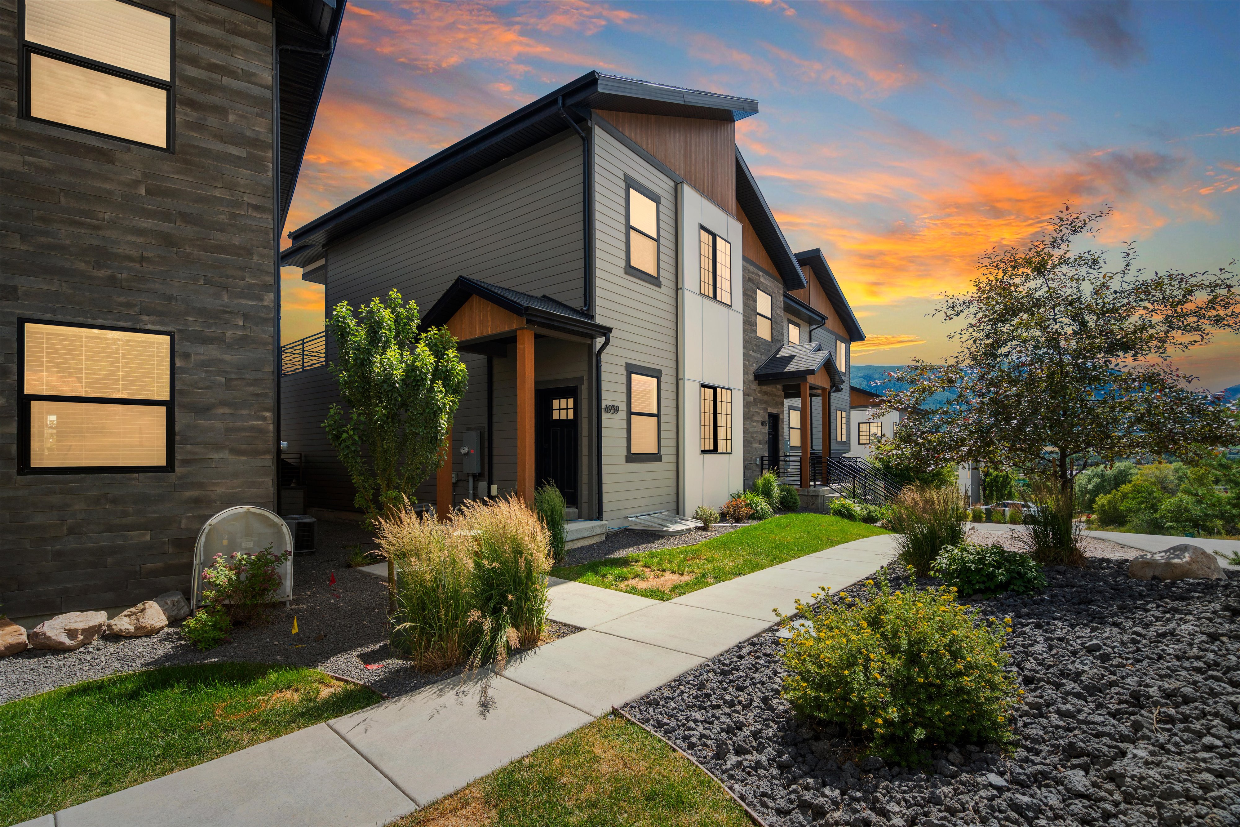 Contemporary multi-level exterior with varied siding, prominent black-framed windows, and a covered entry