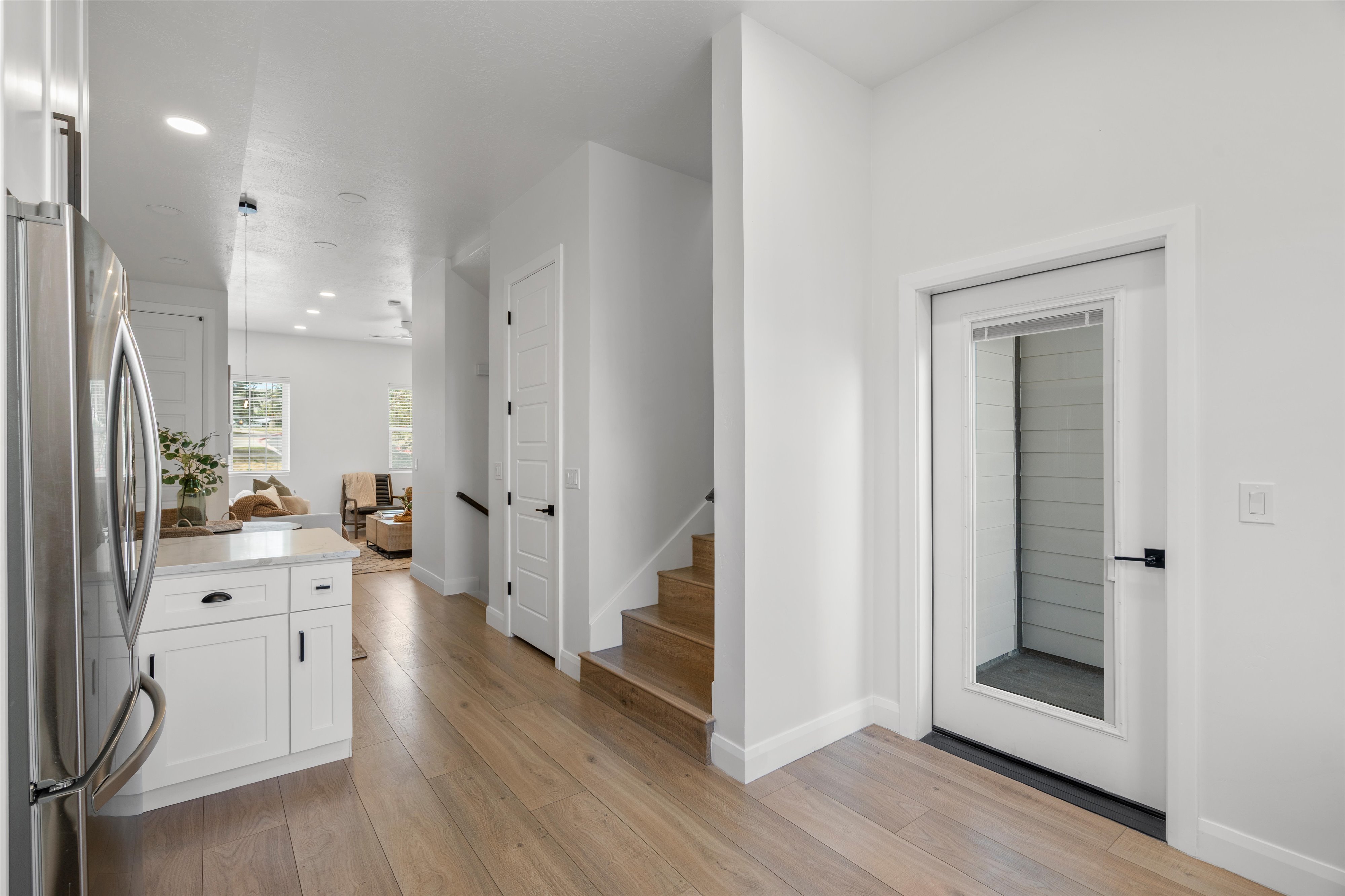 Entryway featuring a glass-panel door, wood-finish flooring, and crisp white walls