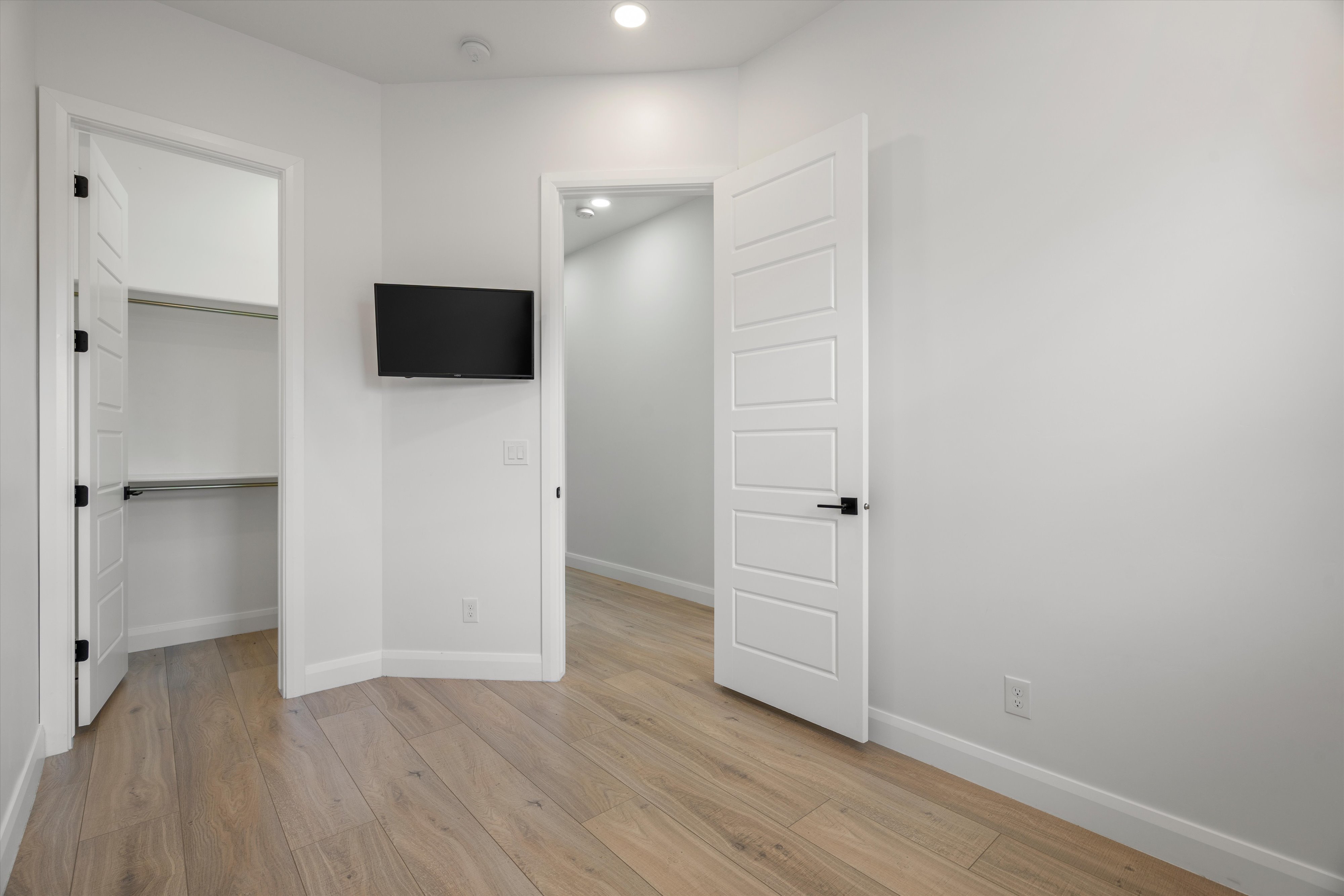 Room featuring wood-finish flooring, recessed lighting, white trim, and a built-in closet with shelving and hanging rod