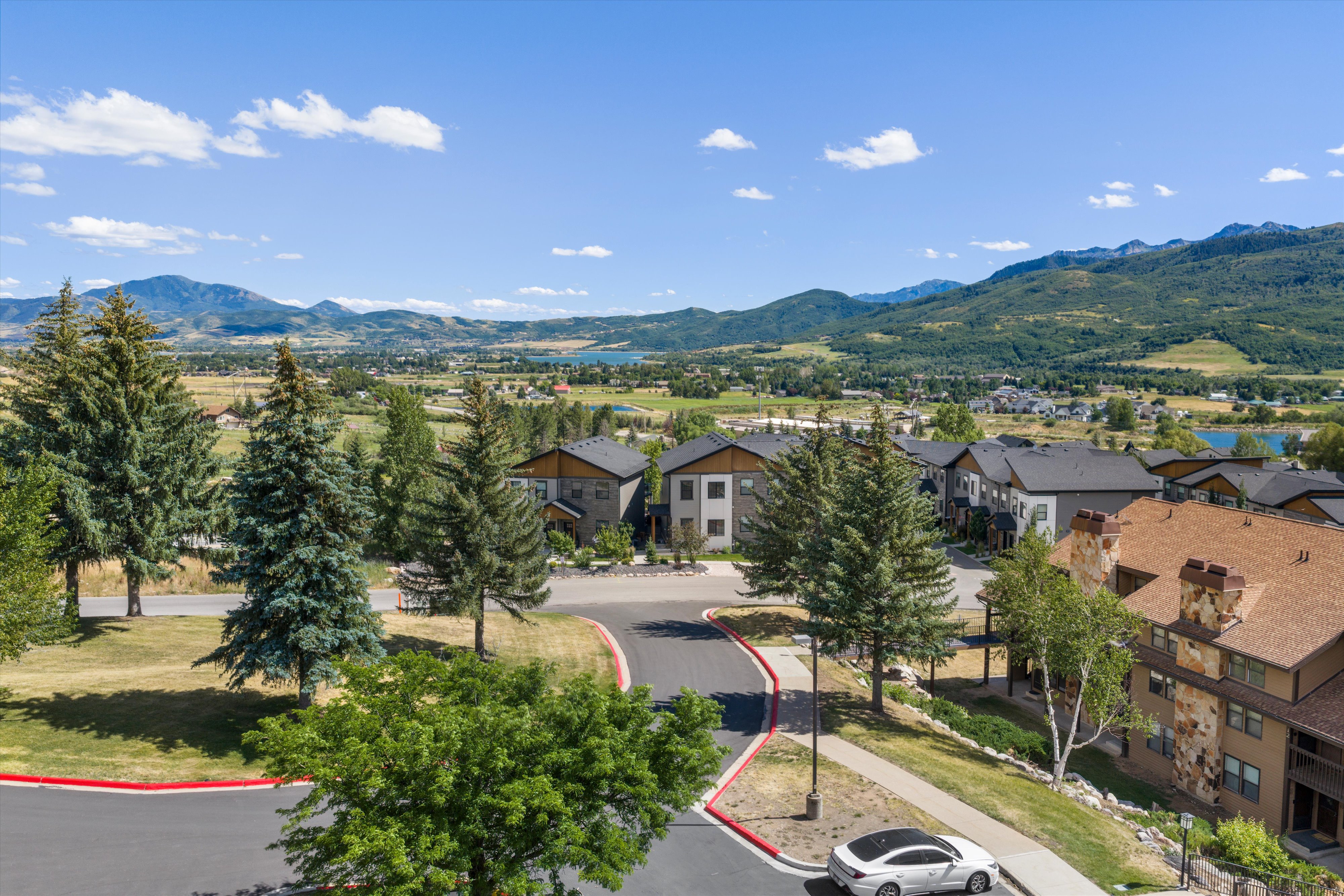 Residential development featuring modern architecture, extensive landscaping with mature trees, and a paved street
