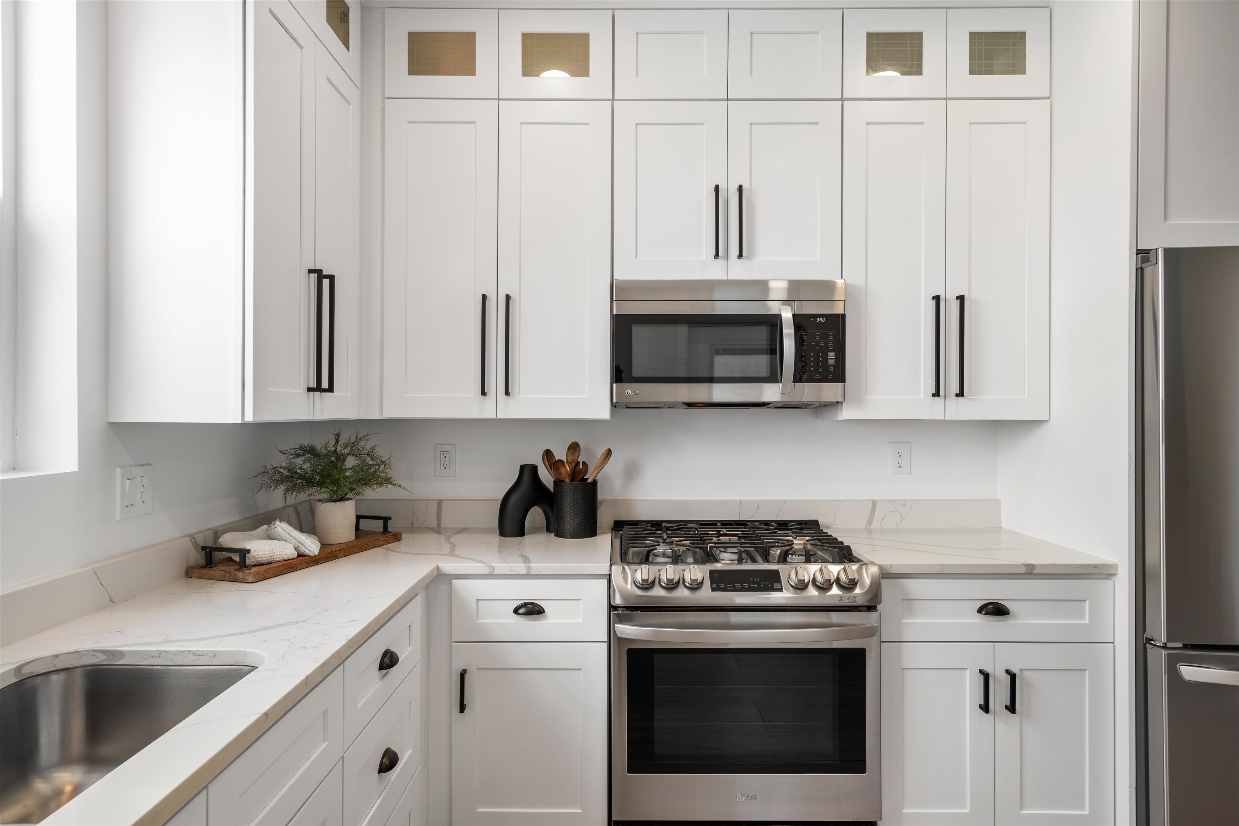 Contemporary kitchen featuring white shaker cabinetry, stainless steel appliances, marble-look countertops, and a stainless steel undermount sink