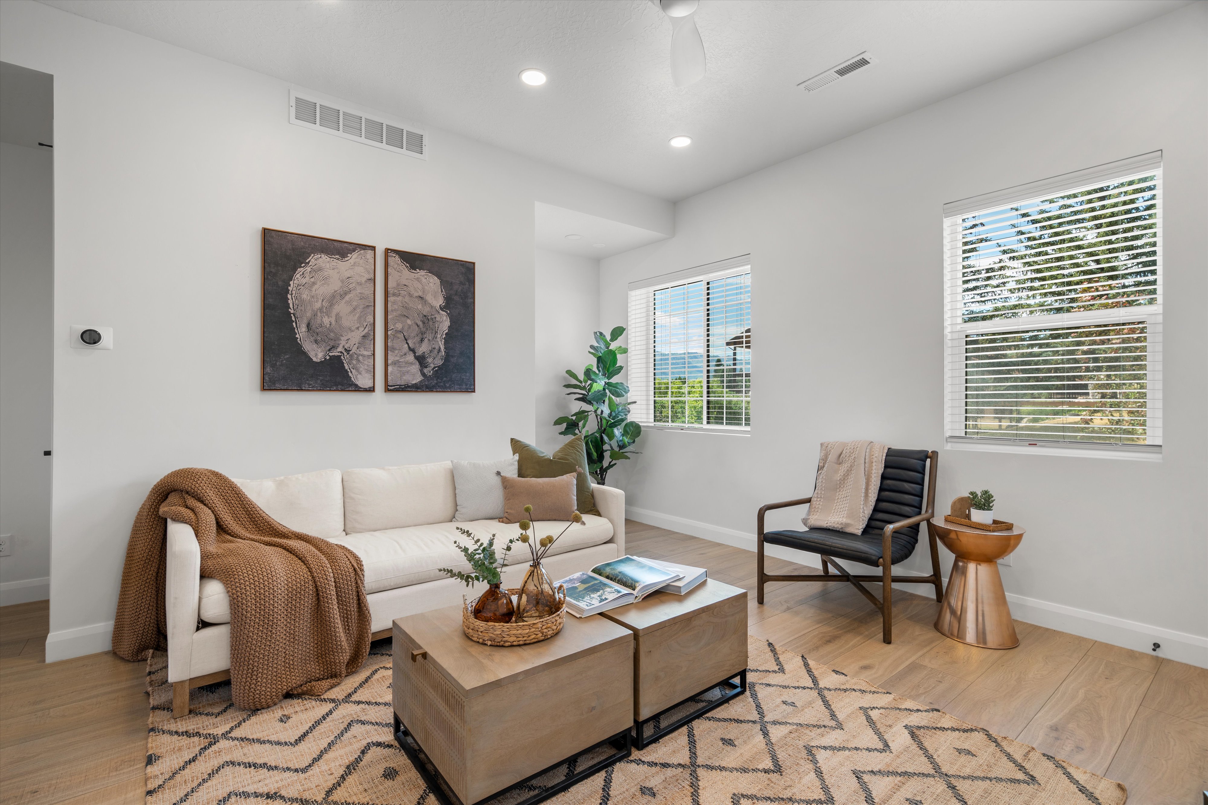 Bright living area featuring wood-finish flooring, recessed lighting, and two windows providing natural light