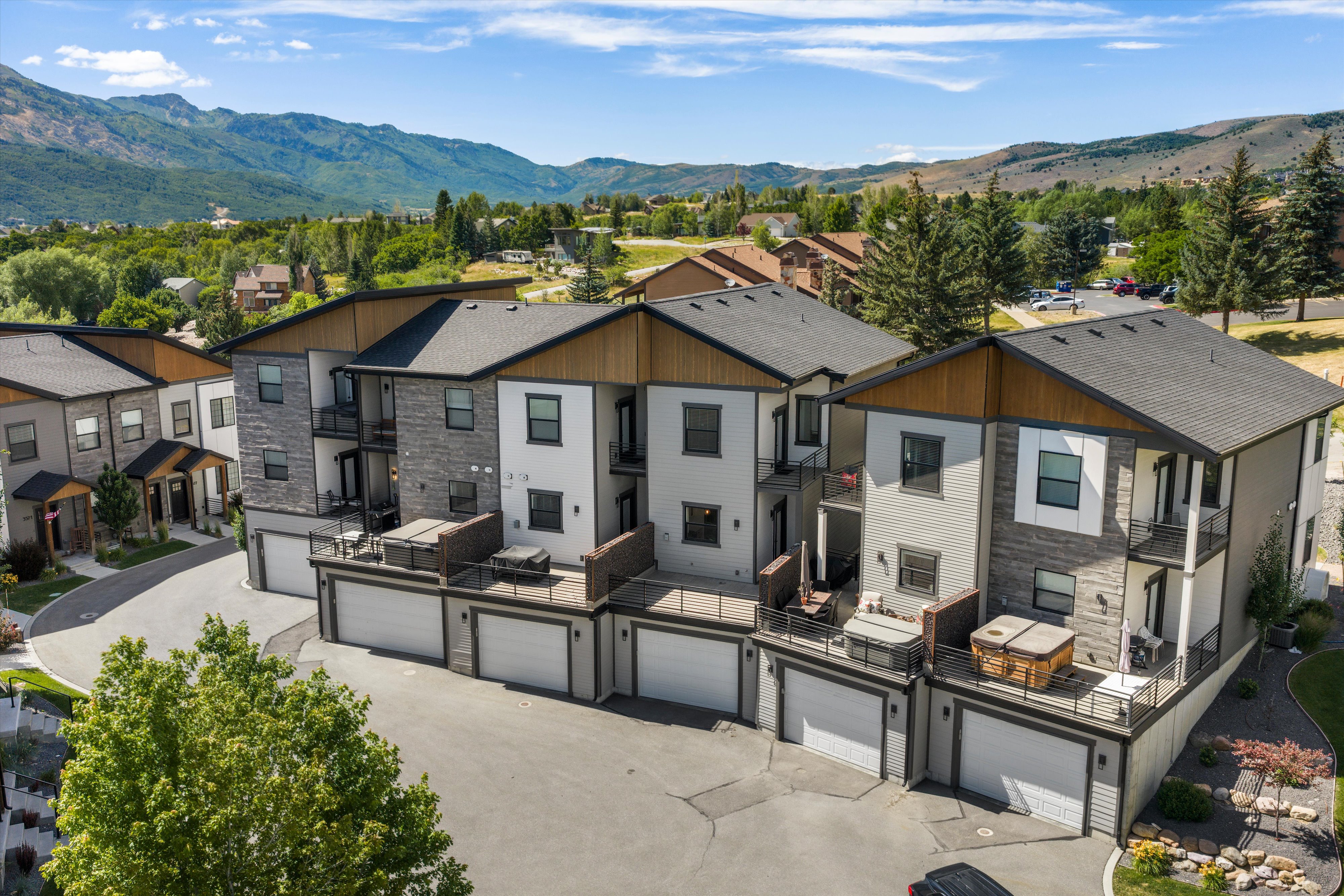 Contemporary multi-level residences featuring attached garages, private balconies, and stone and wood-finish exterior accents