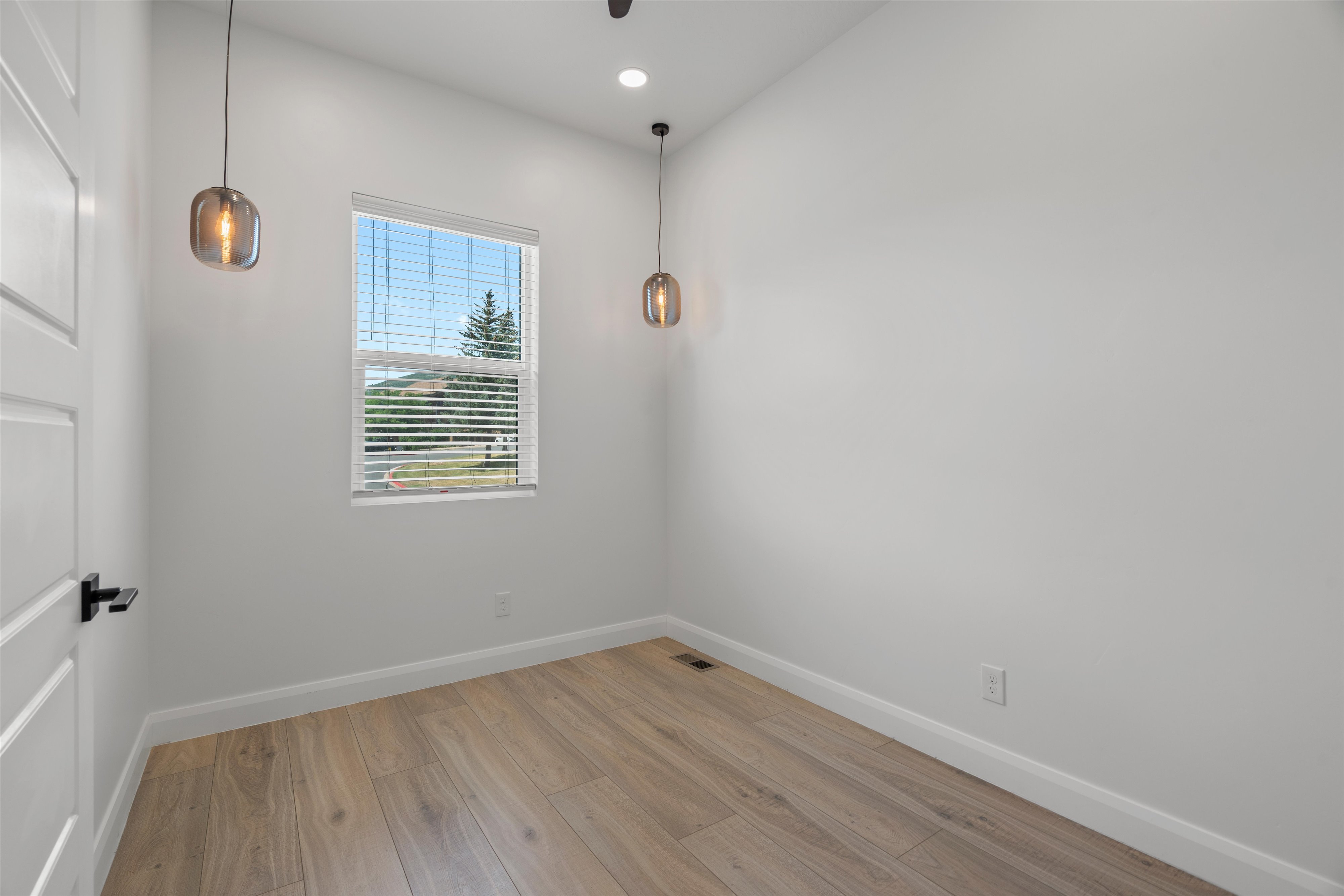 Room featuring wood-finish flooring, white baseboards, and a single window with blinds