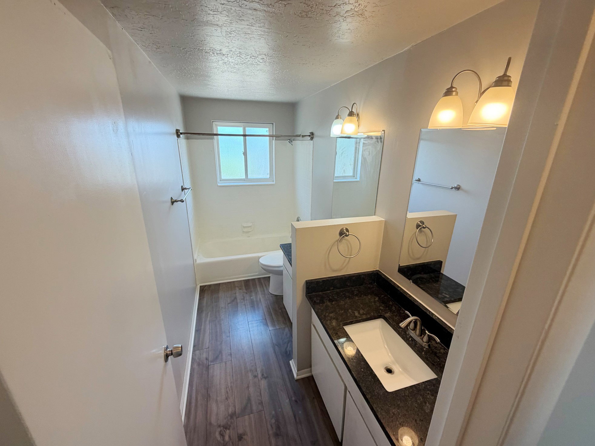 Bathroom featuring a single vanity with a dark countertop, undermount sink, and chrome fixtures