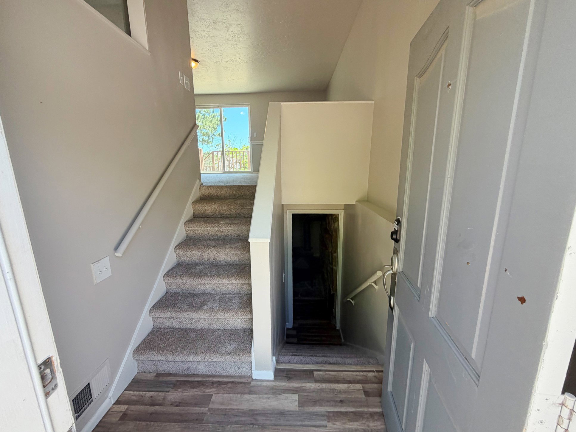 Foyer with wood-finish flooring extending to a carpeted staircase and a sliding glass door
