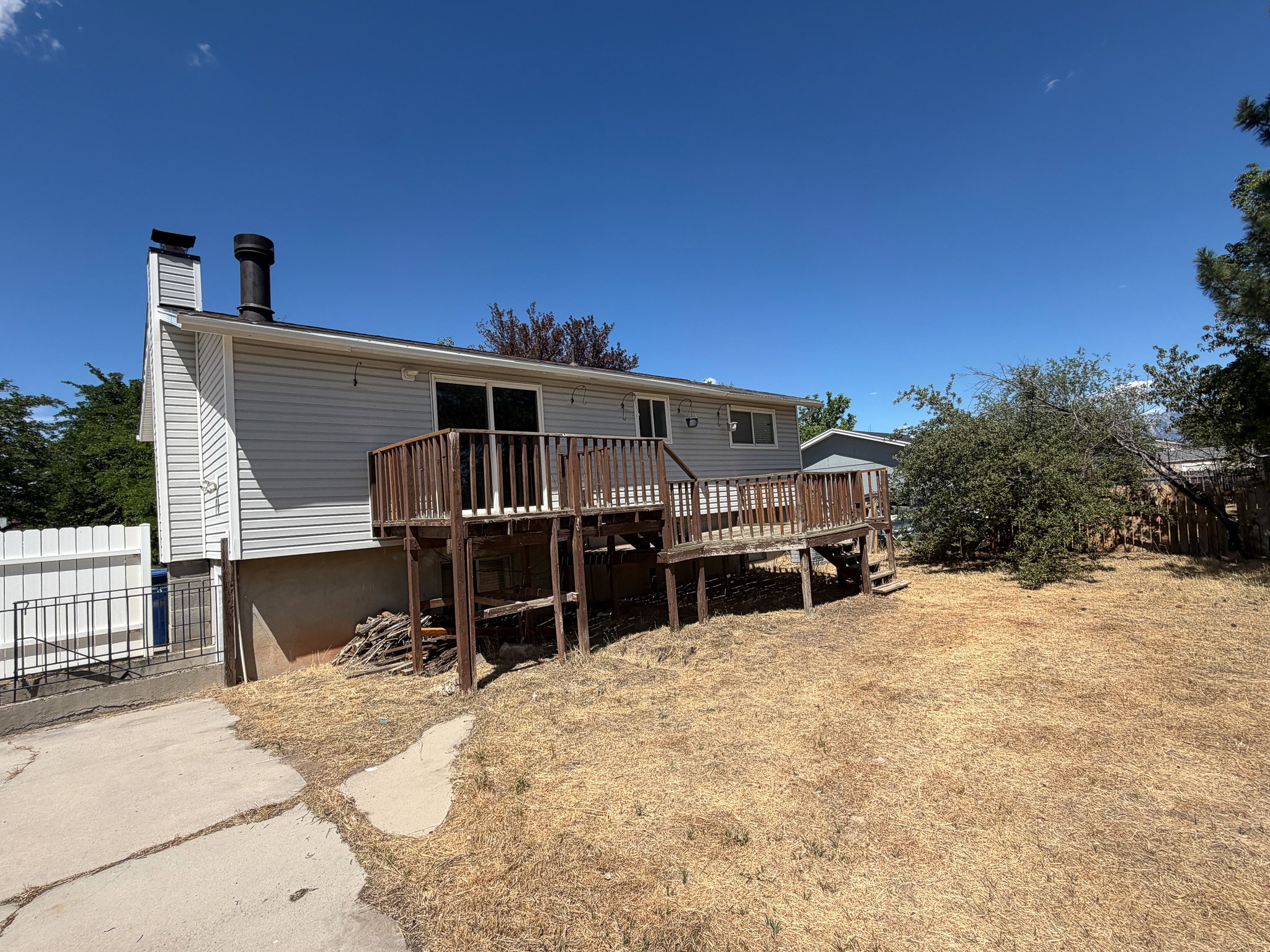 Rear exterior featuring a wood deck with railing and stairs, vinyl siding, and a sliding glass door