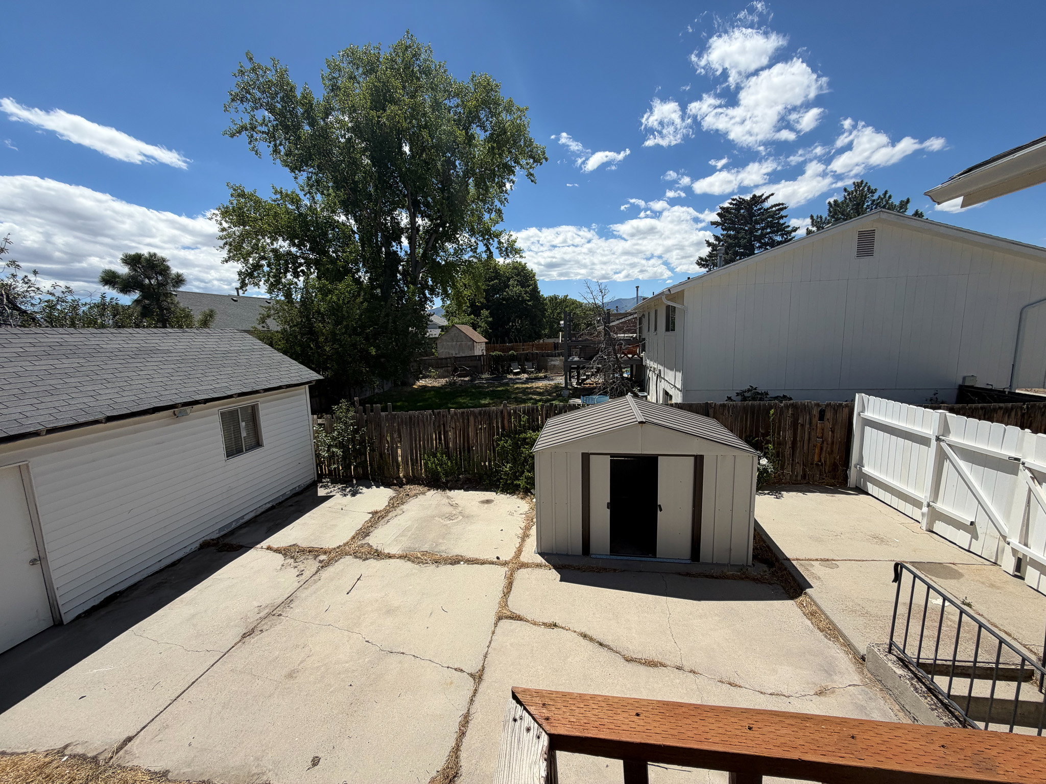 Concrete patio area featuring a detached garage and a storage shed