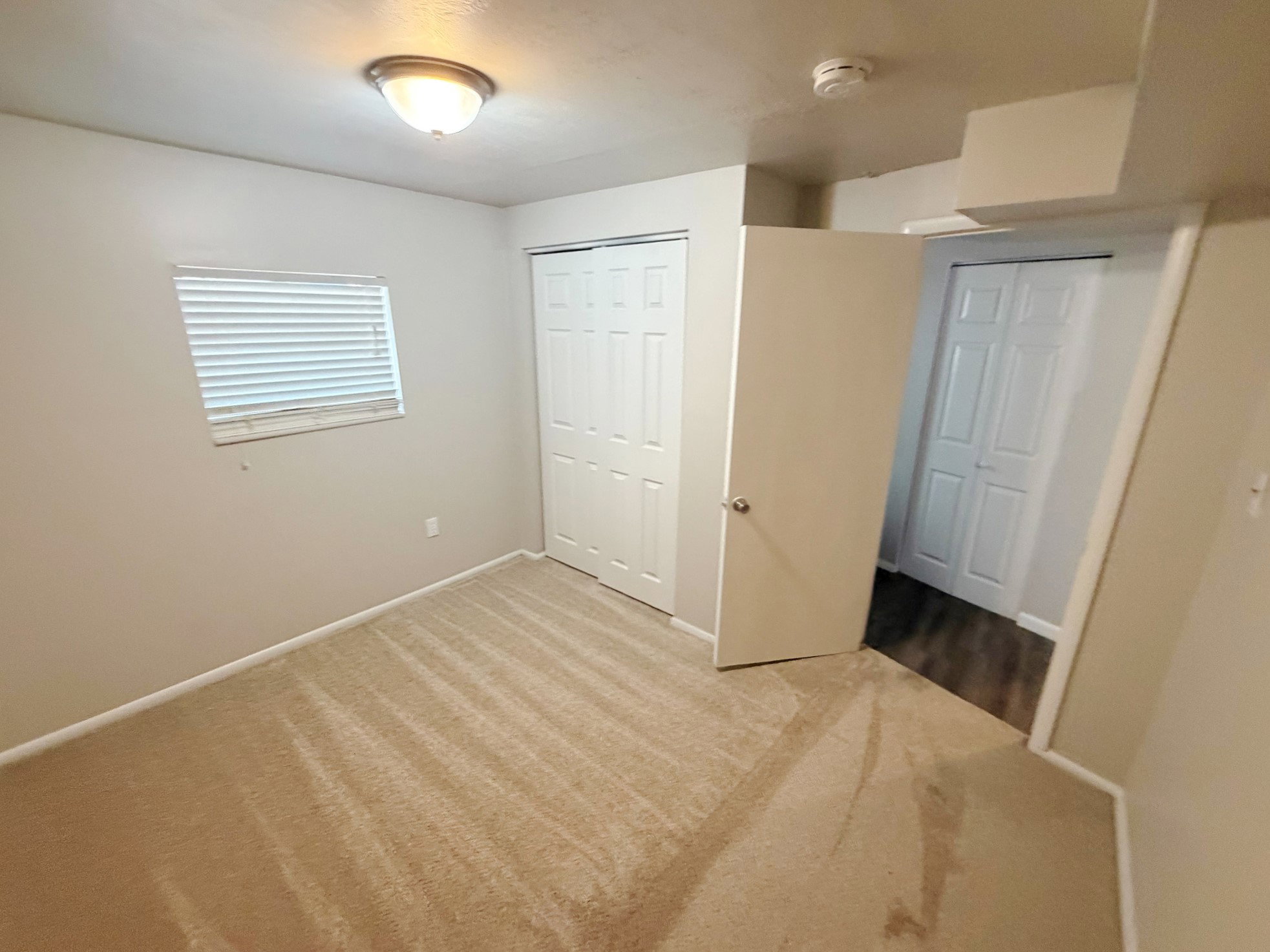 Carpeted room with neutral wall tones and a window featuring horizontal blinds