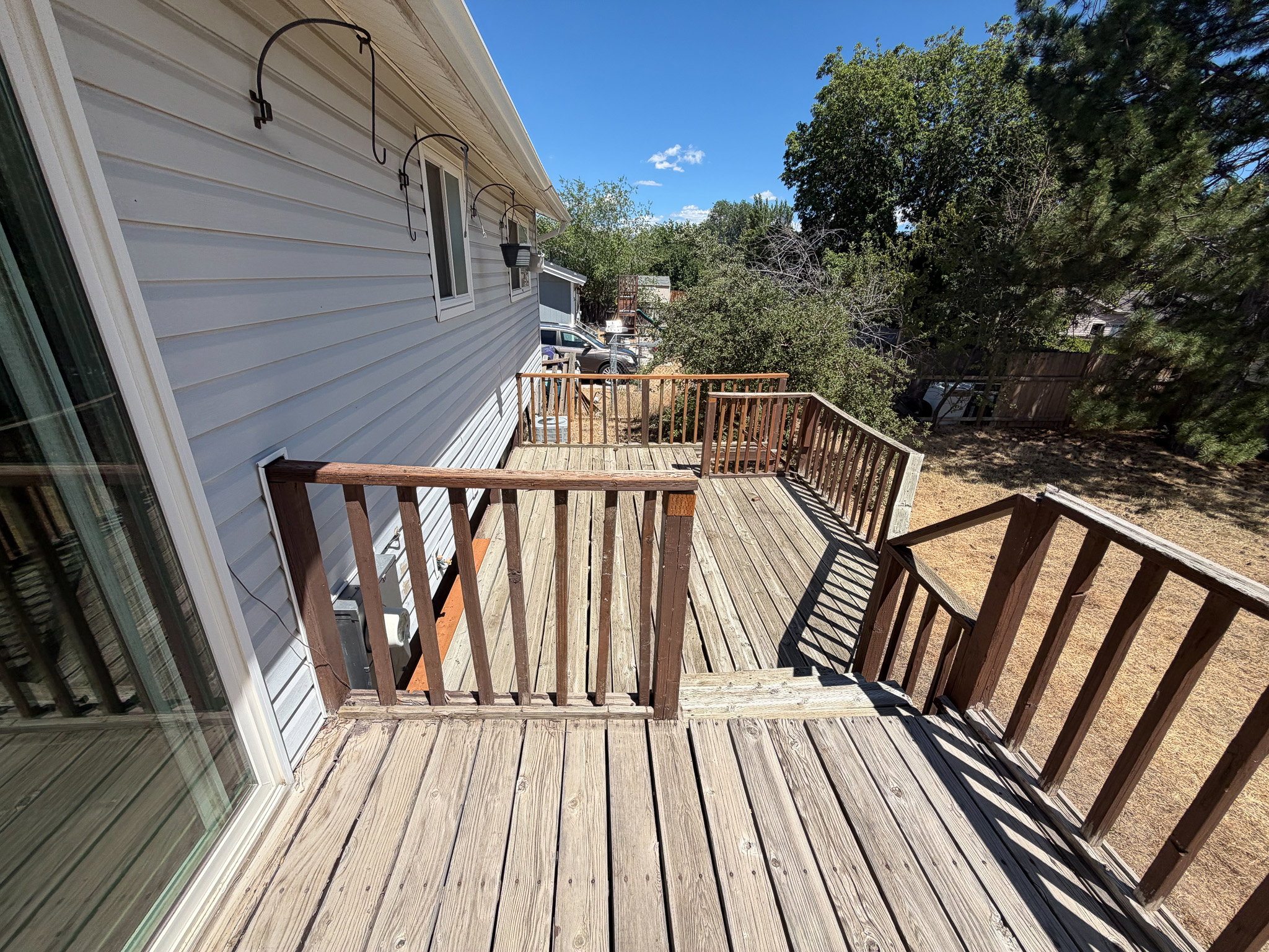 Multi-tiered wood deck with stairs, featuring wood baluster railings and a sliding glass door entry