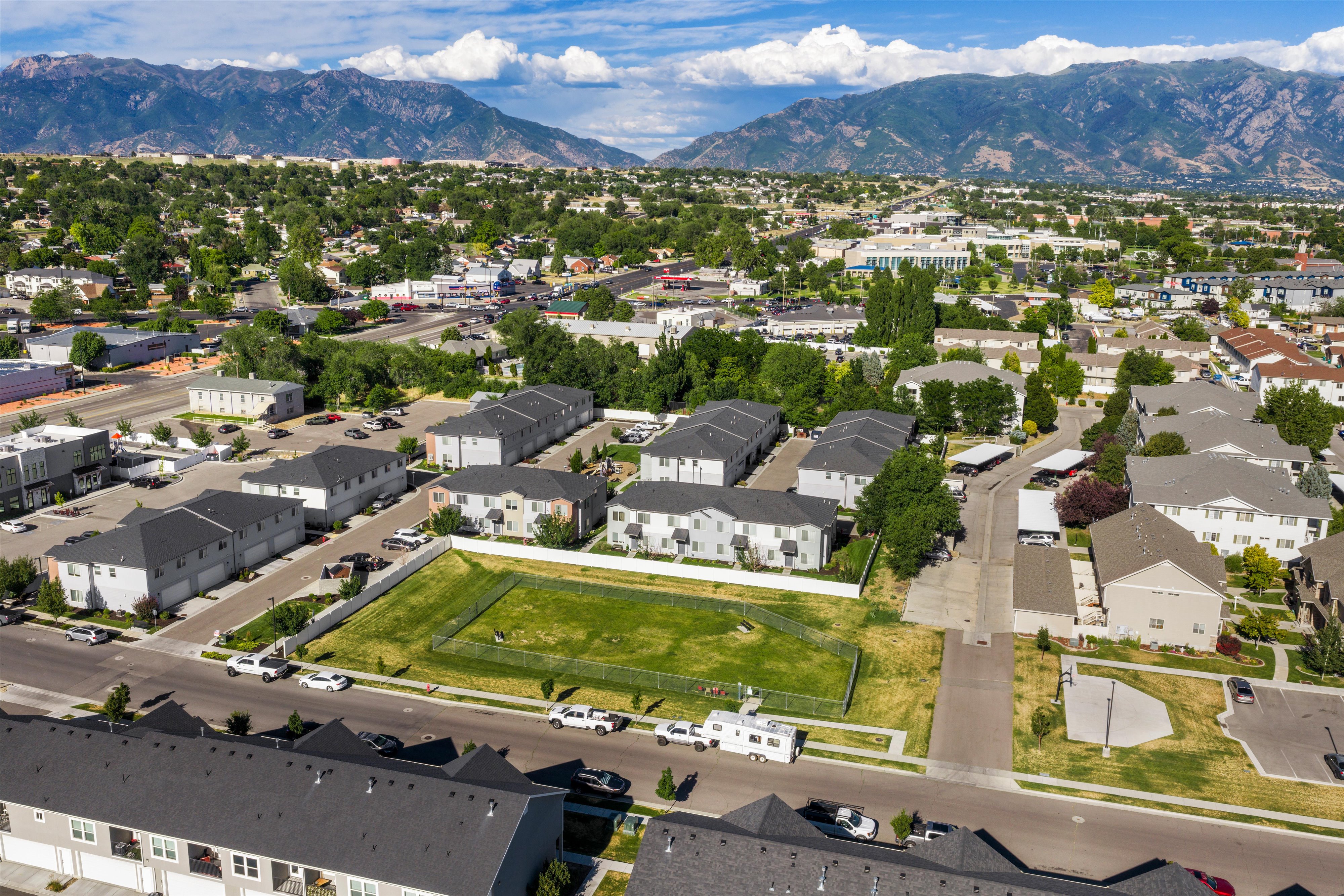 Expansive land parcel with surrounding residential and commercial structures, featuring a vibrant green space and clear perimeter fencing