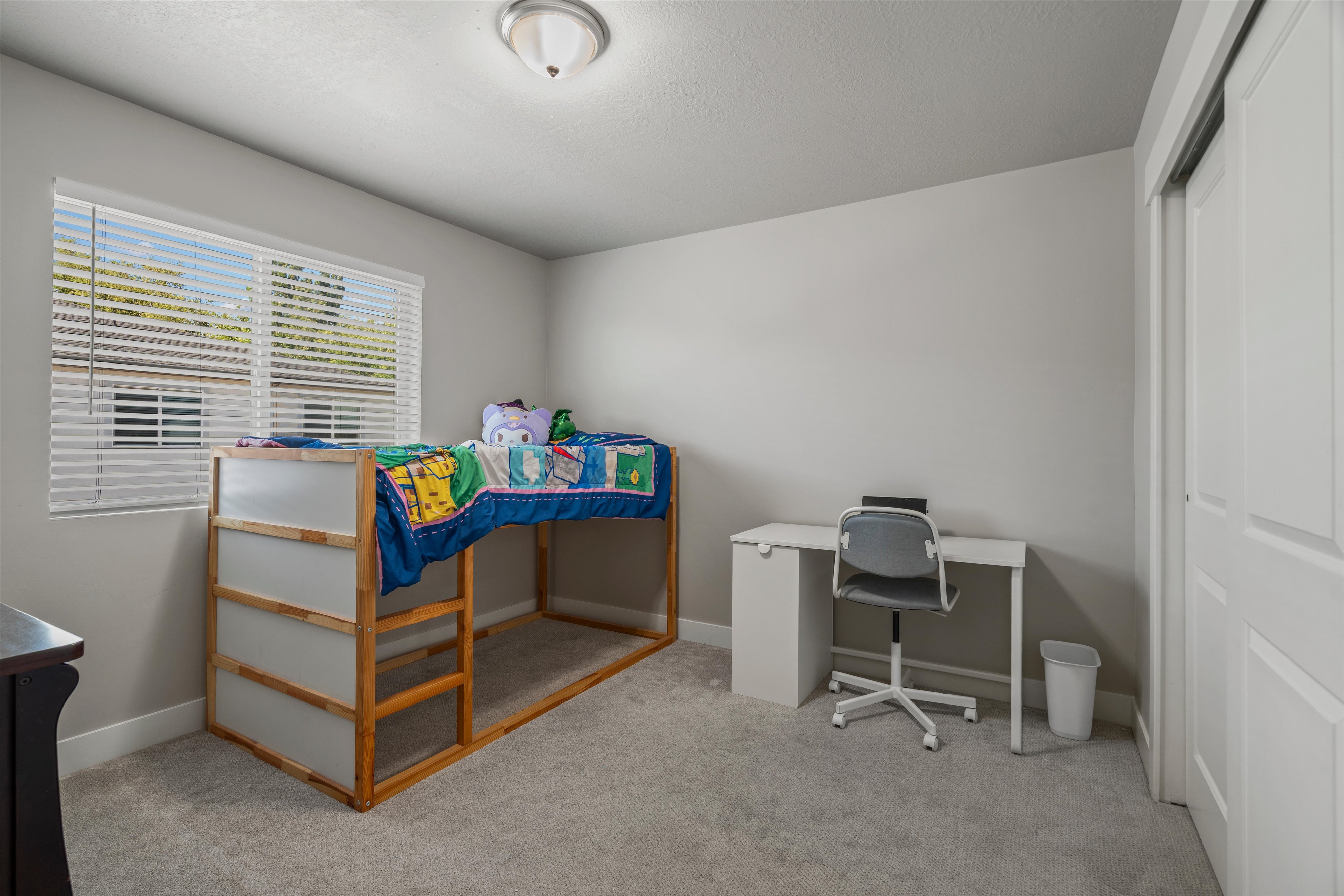 Carpeted room with a window featuring horizontal blinds