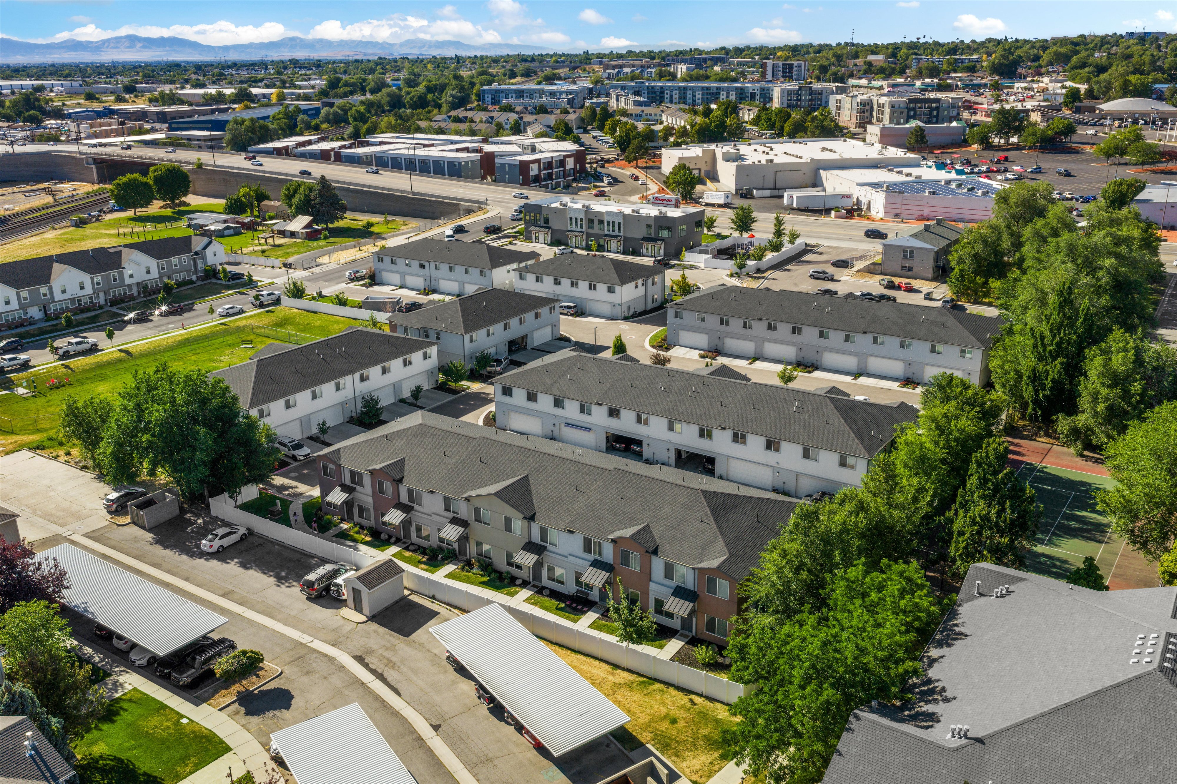 Aerial view of a residential community featuring multi-unit properties with dark shingle roofs