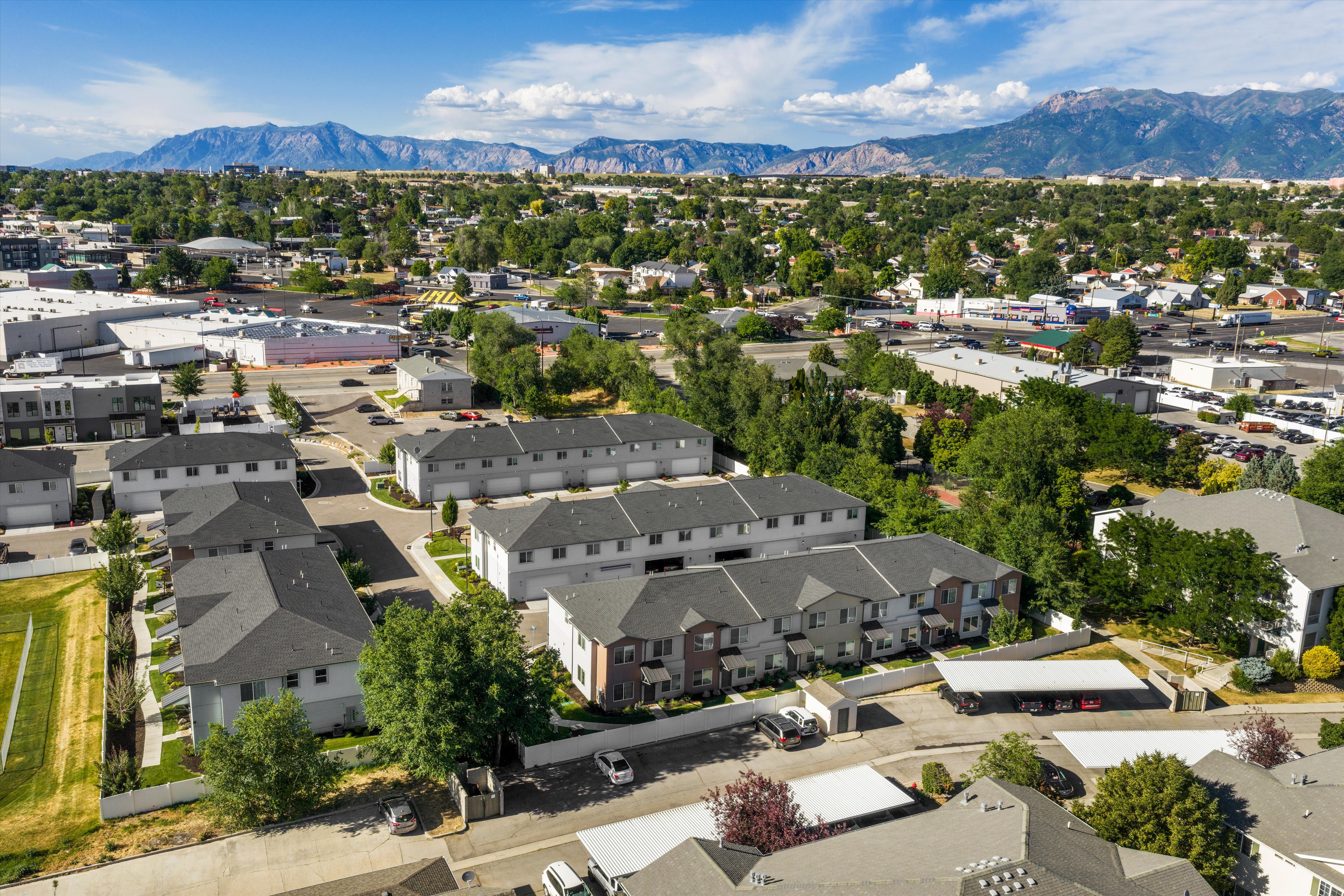 Aerial perspective showcasing a complex of multi-story townhomes with gray shingle roofs