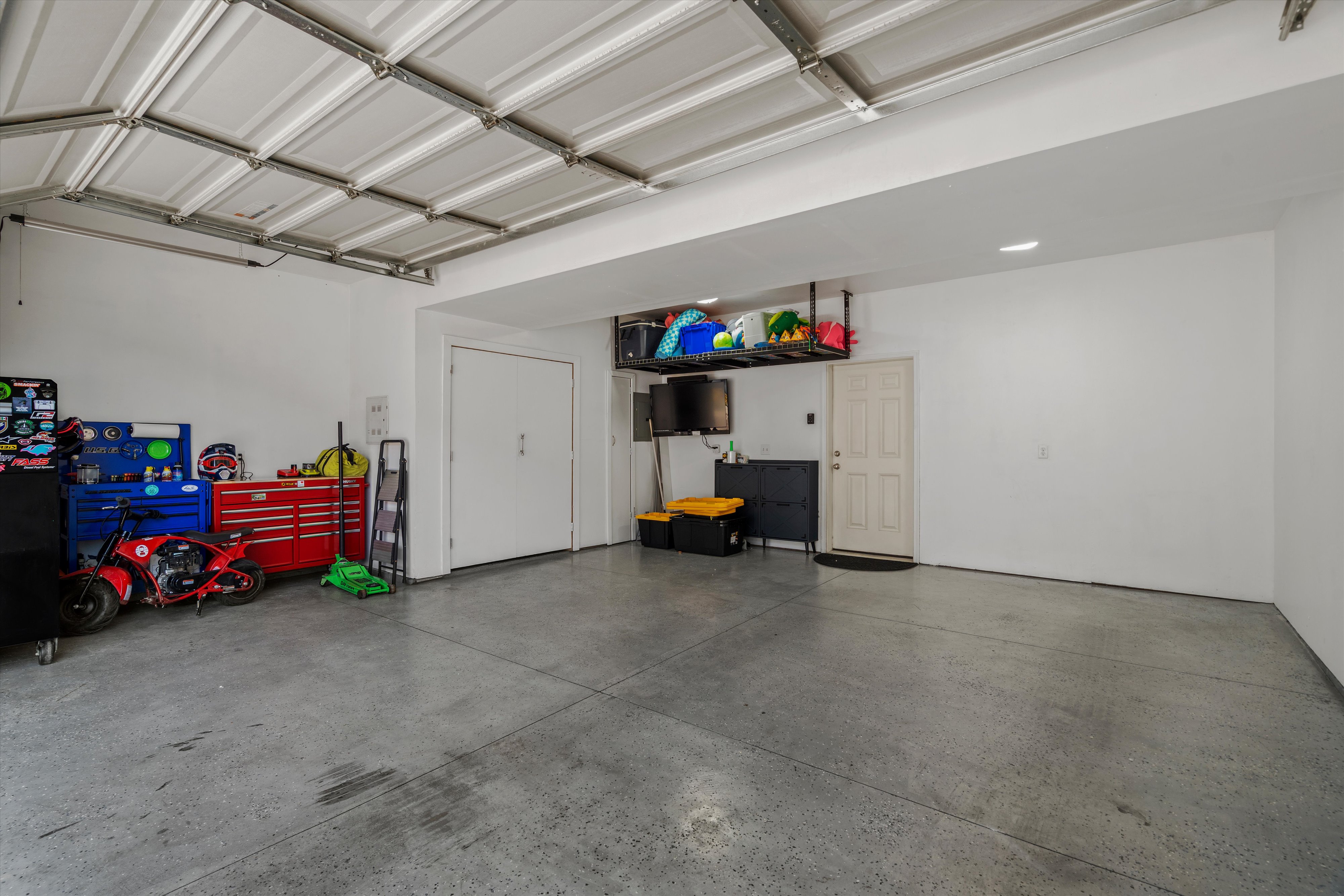 Spacious garage featuring a durable epoxy-coated concrete floor, white walls, and a sectional garage door