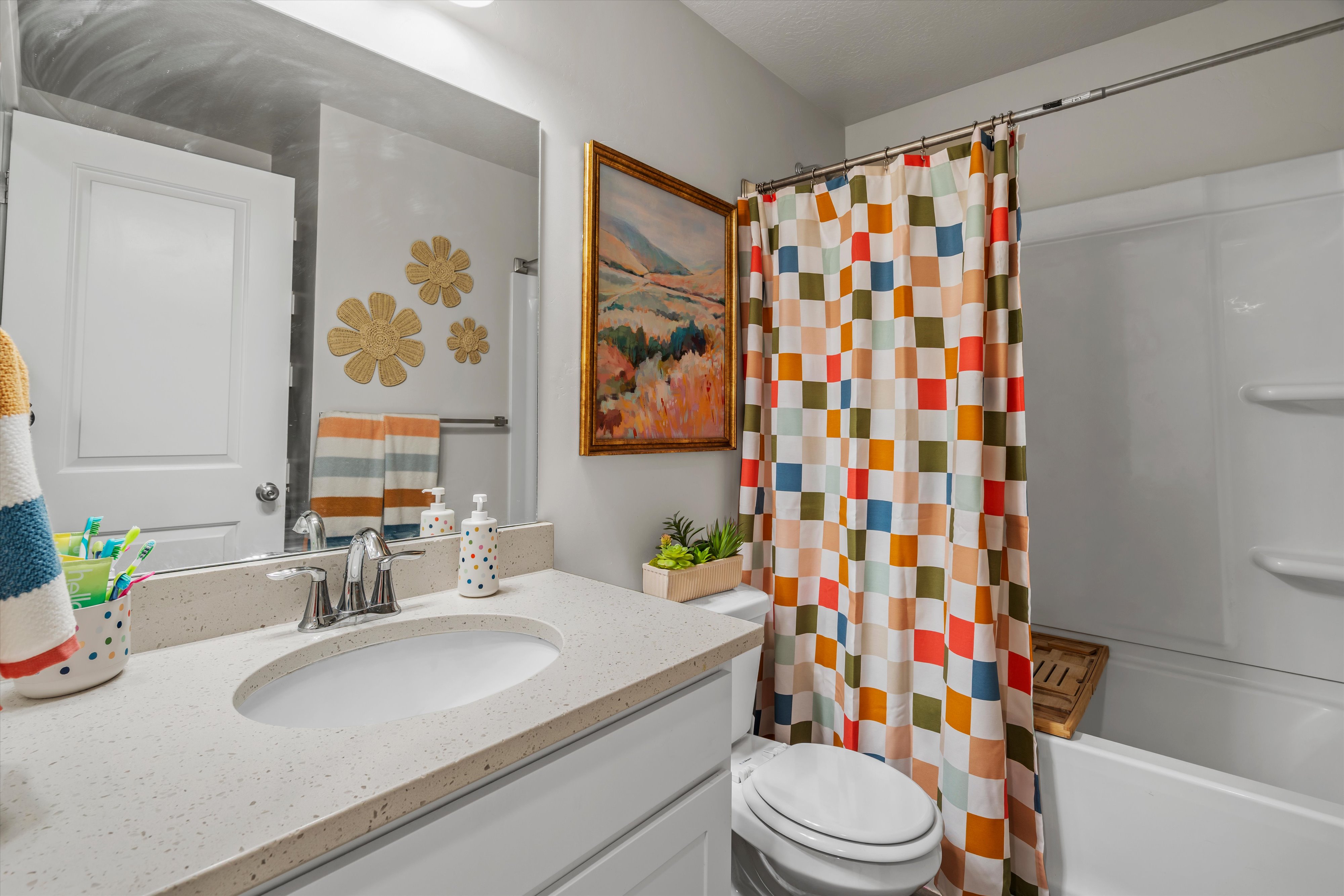 Bathroom featuring a single vanity with an integrated sink, polished chrome faucet, and light-toned solid surface countertop