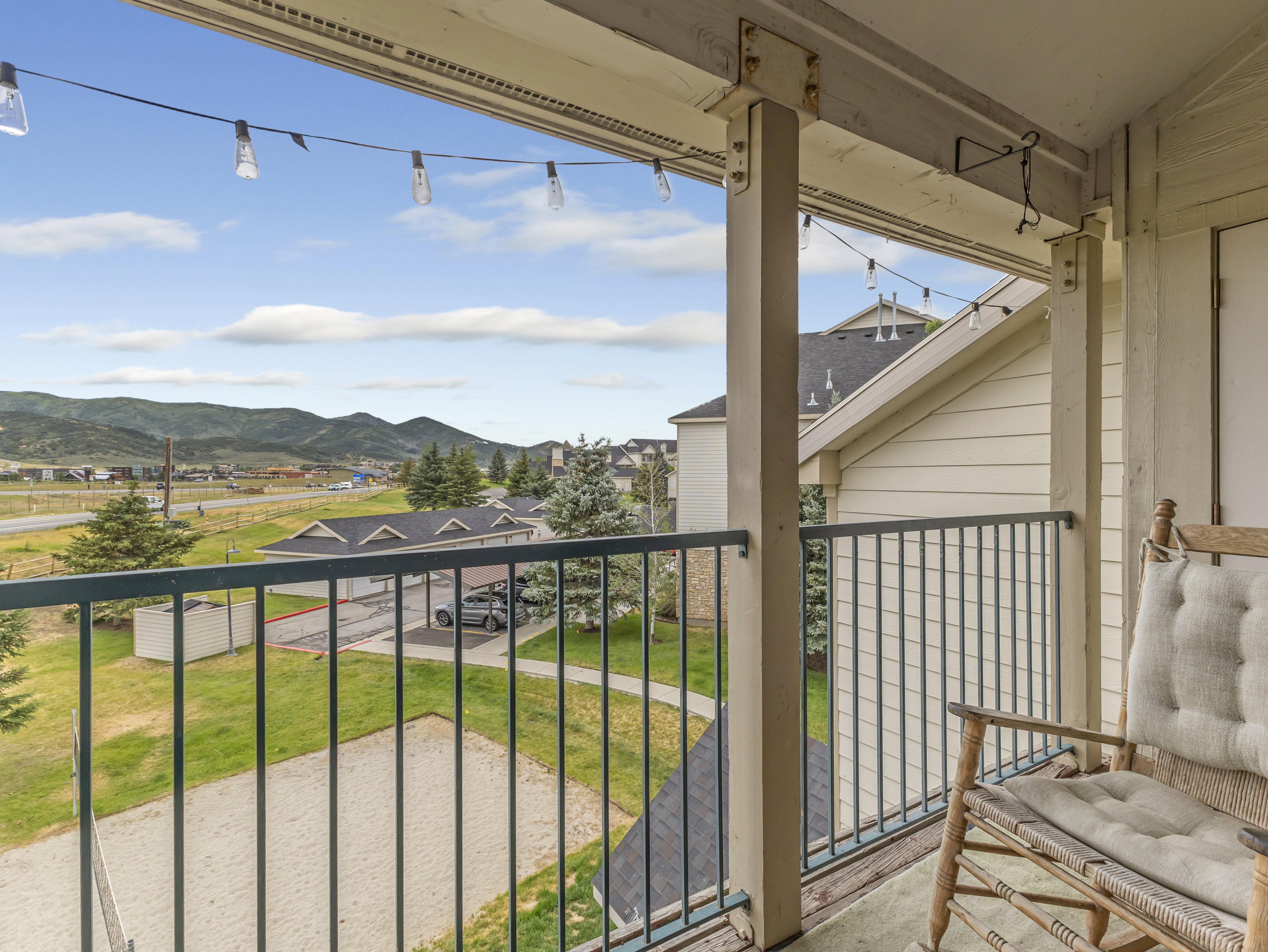 Exterior balcony featuring string lights, painted wood columns, and a dark metal railing