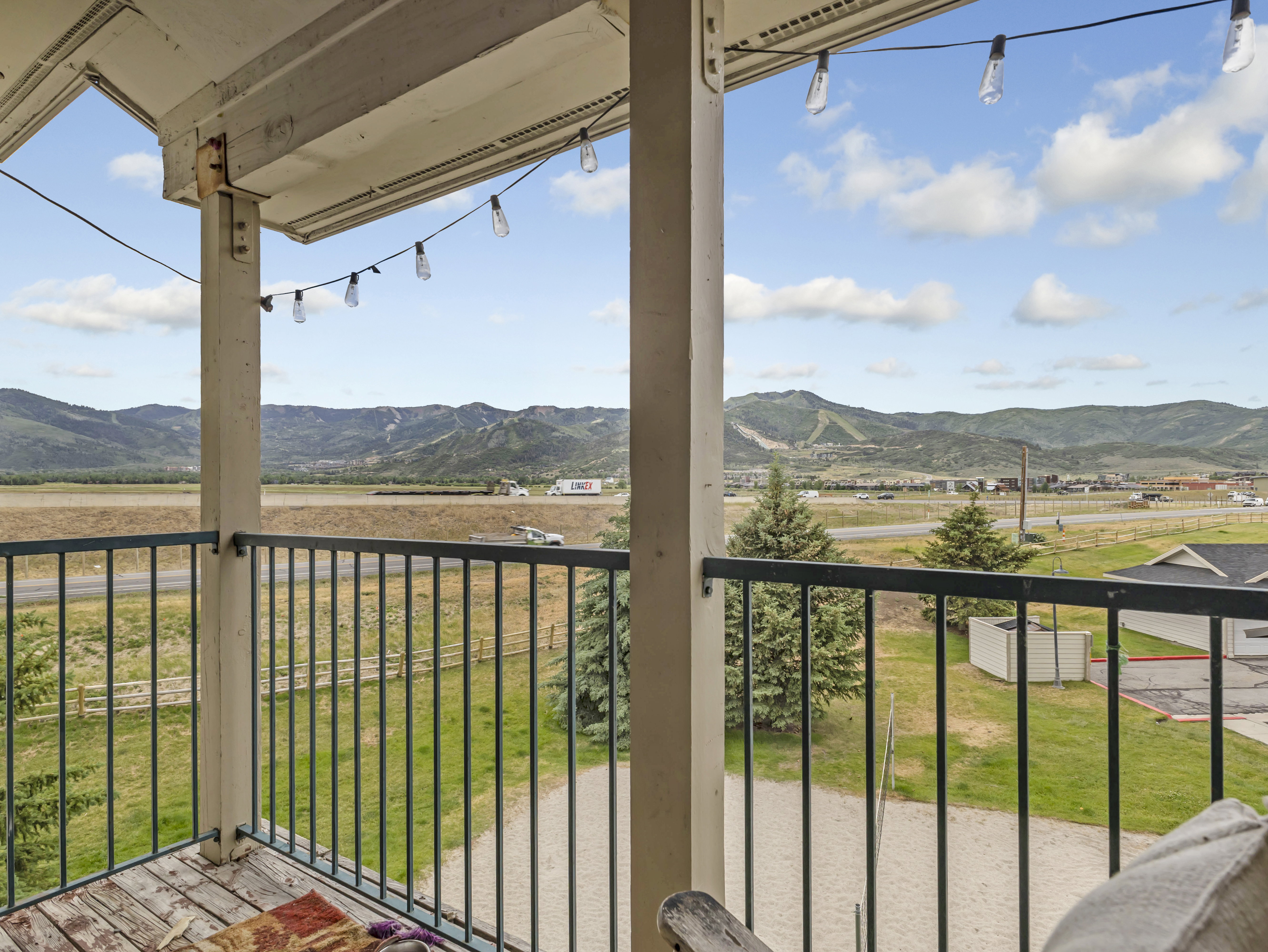 Balcony featuring an open railing, wood-finish flooring, and string lighting