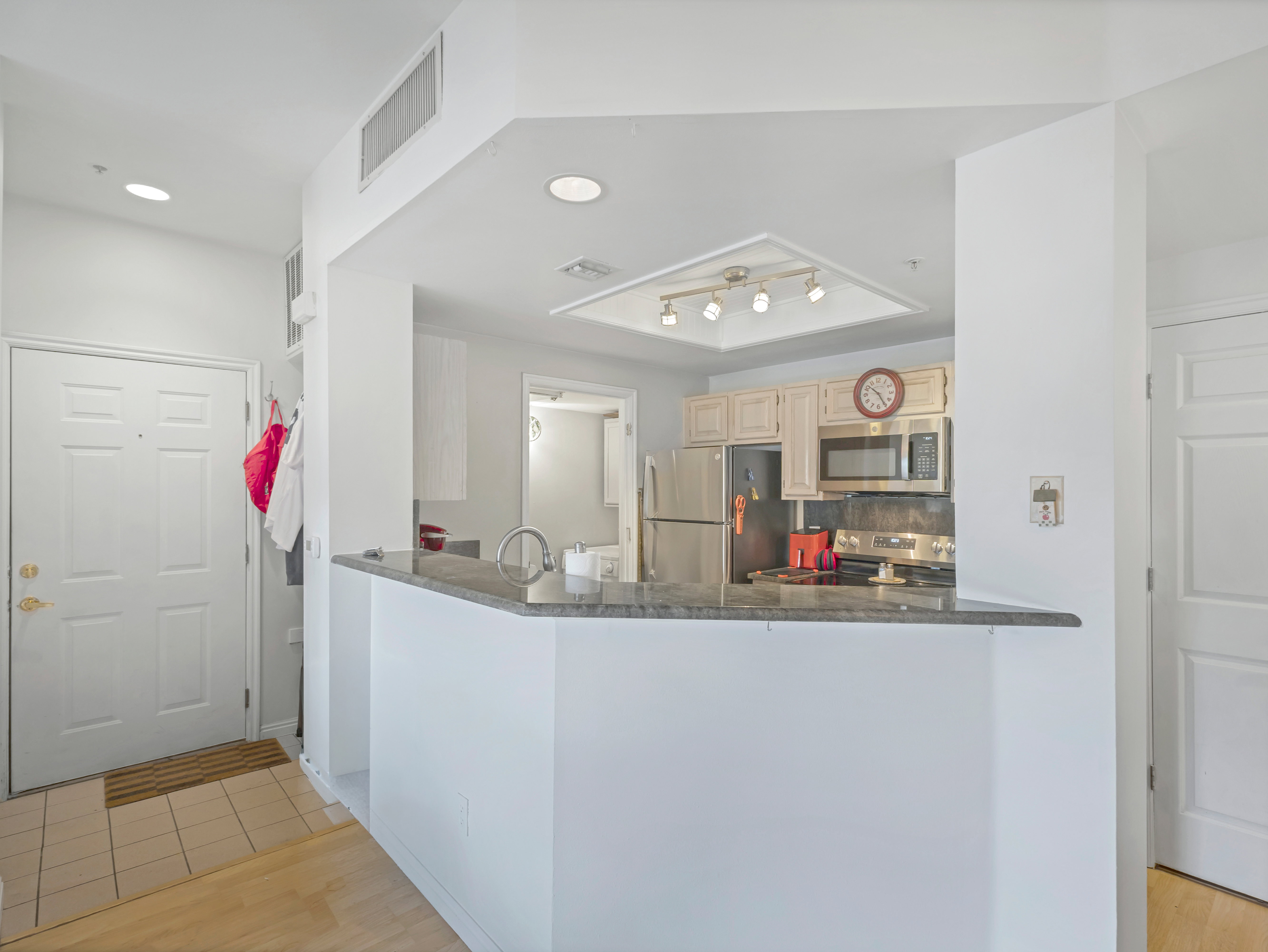 Kitchen with stainless steel appliances, light wood-finish cabinetry, and a dark stone countertop peninsula