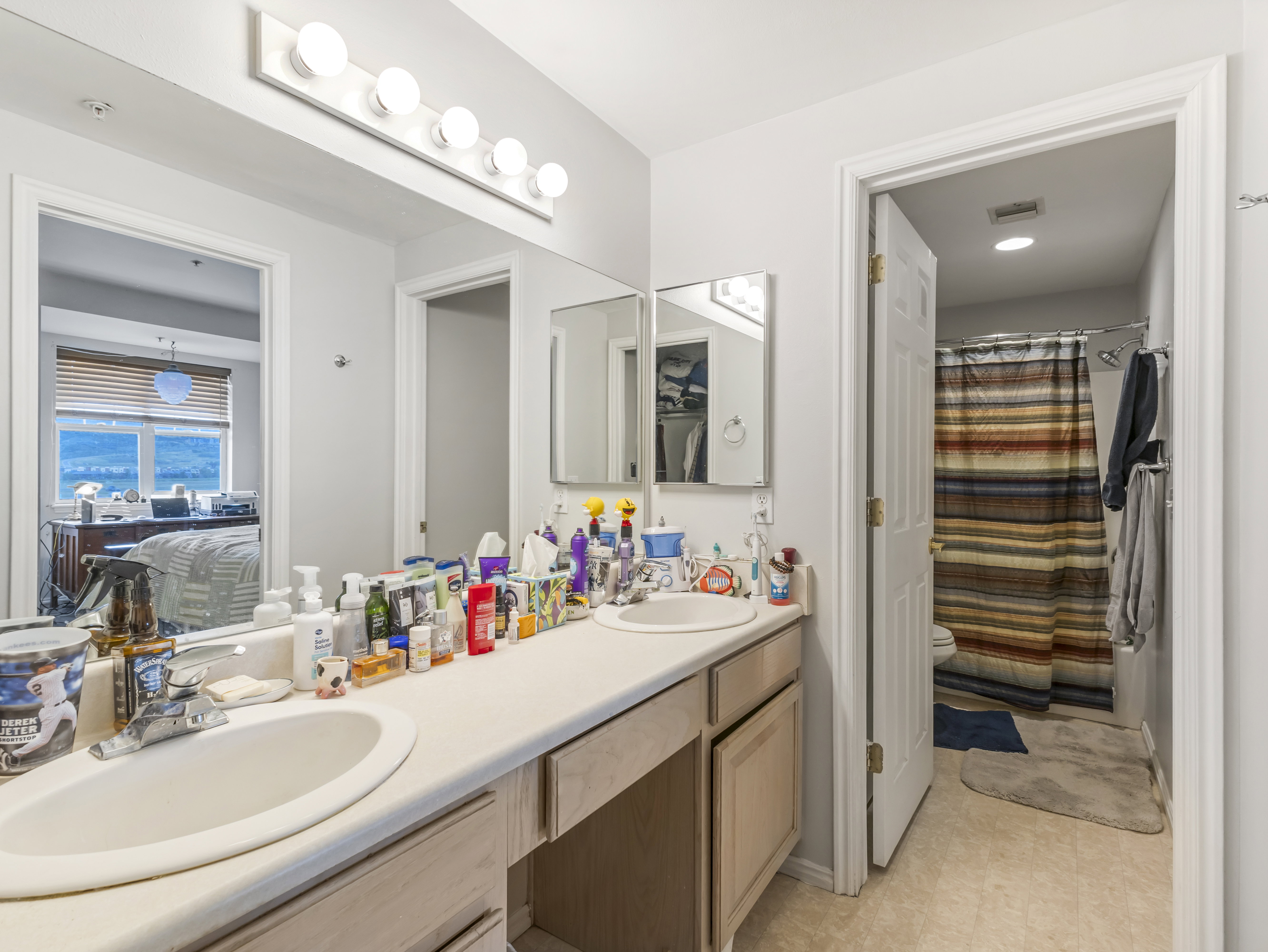 Bathroom featuring a dual-sink vanity with ample counter space, wood-finish cabinetry, and an overhead vanity light fixture