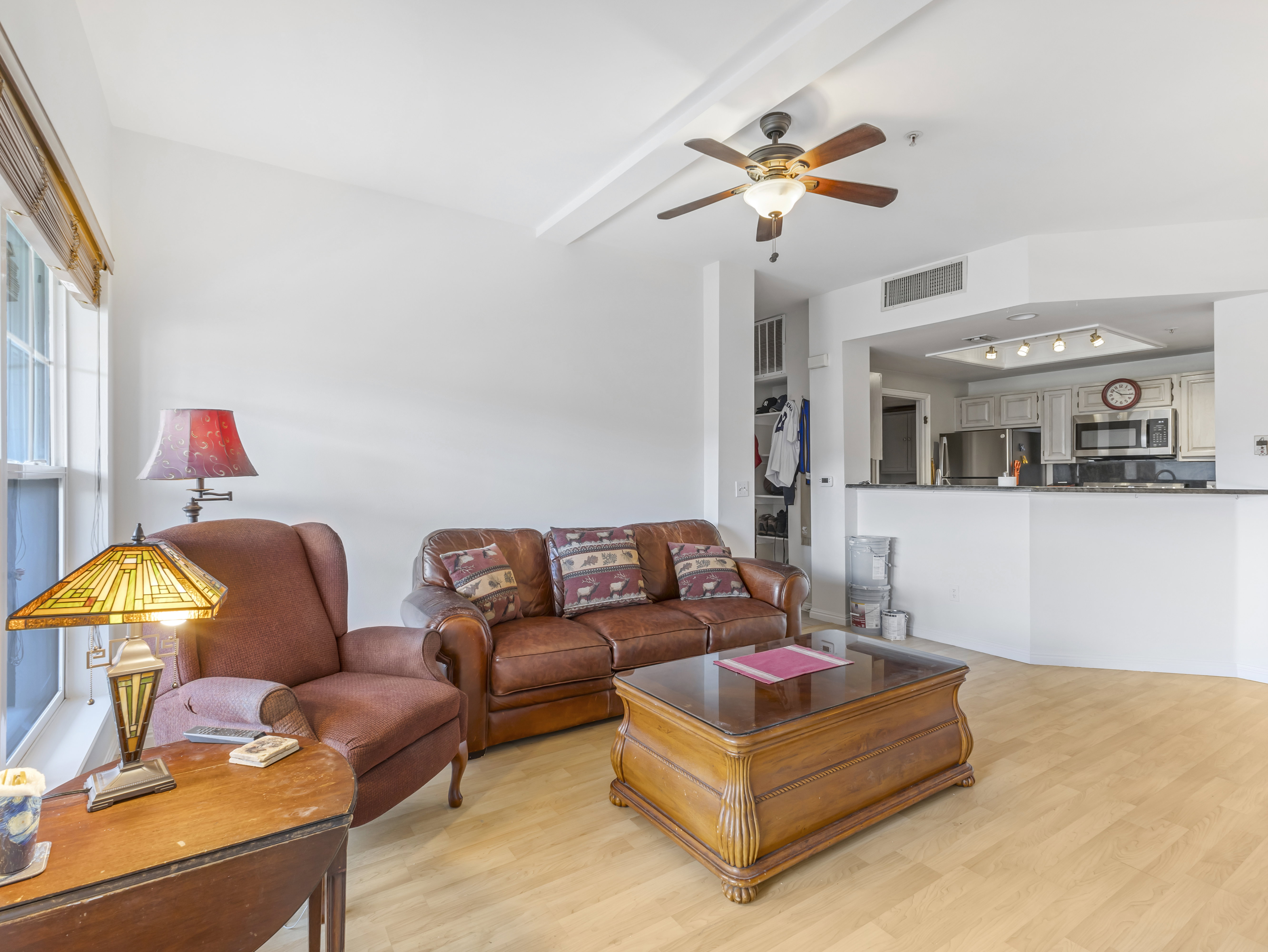 Spacious living area featuring wood-finish flooring, a vaulted ceiling, and an integrated ceiling fan
