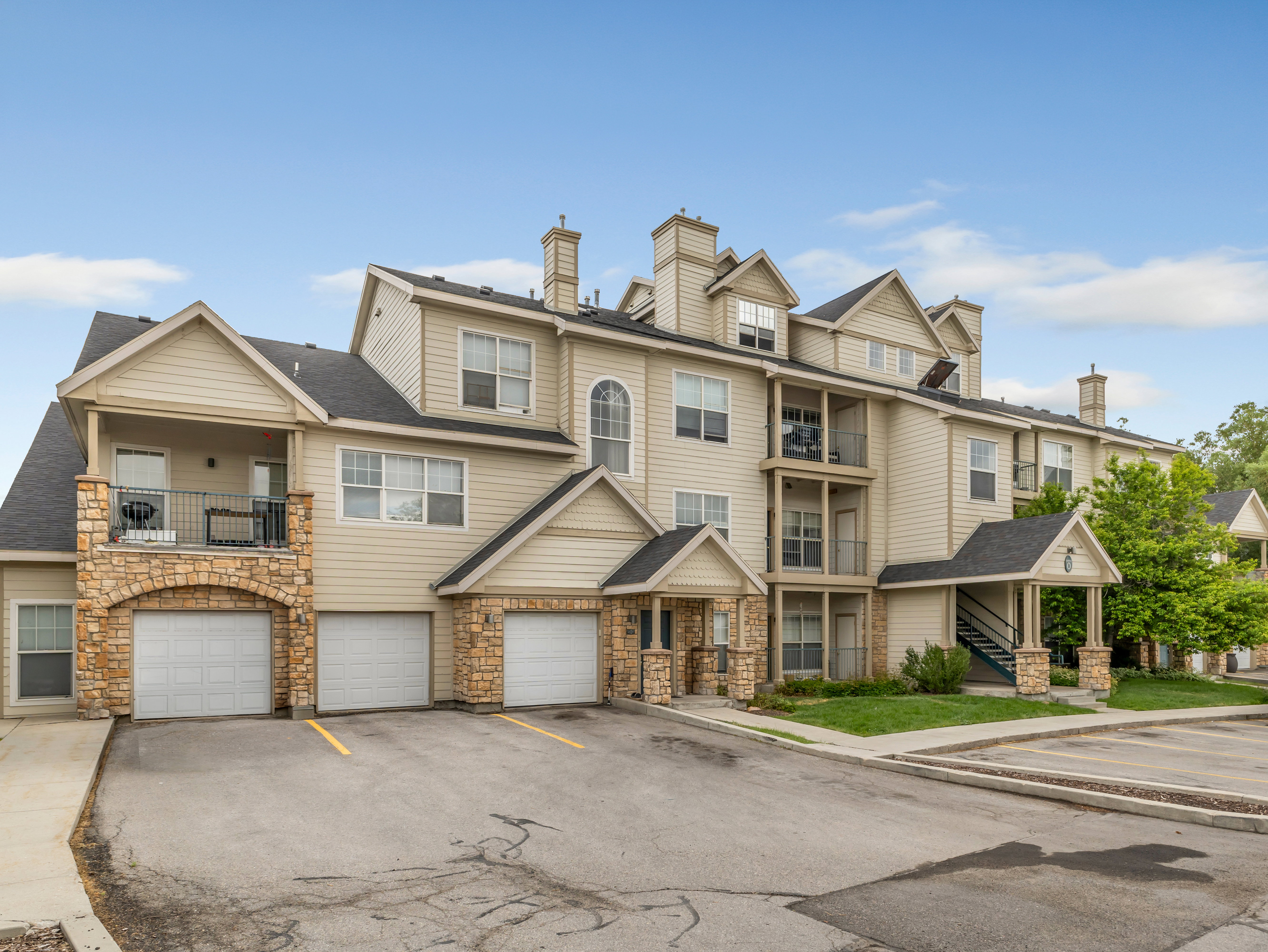 Multi-story residential building with light-toned siding and stone veneer accents
