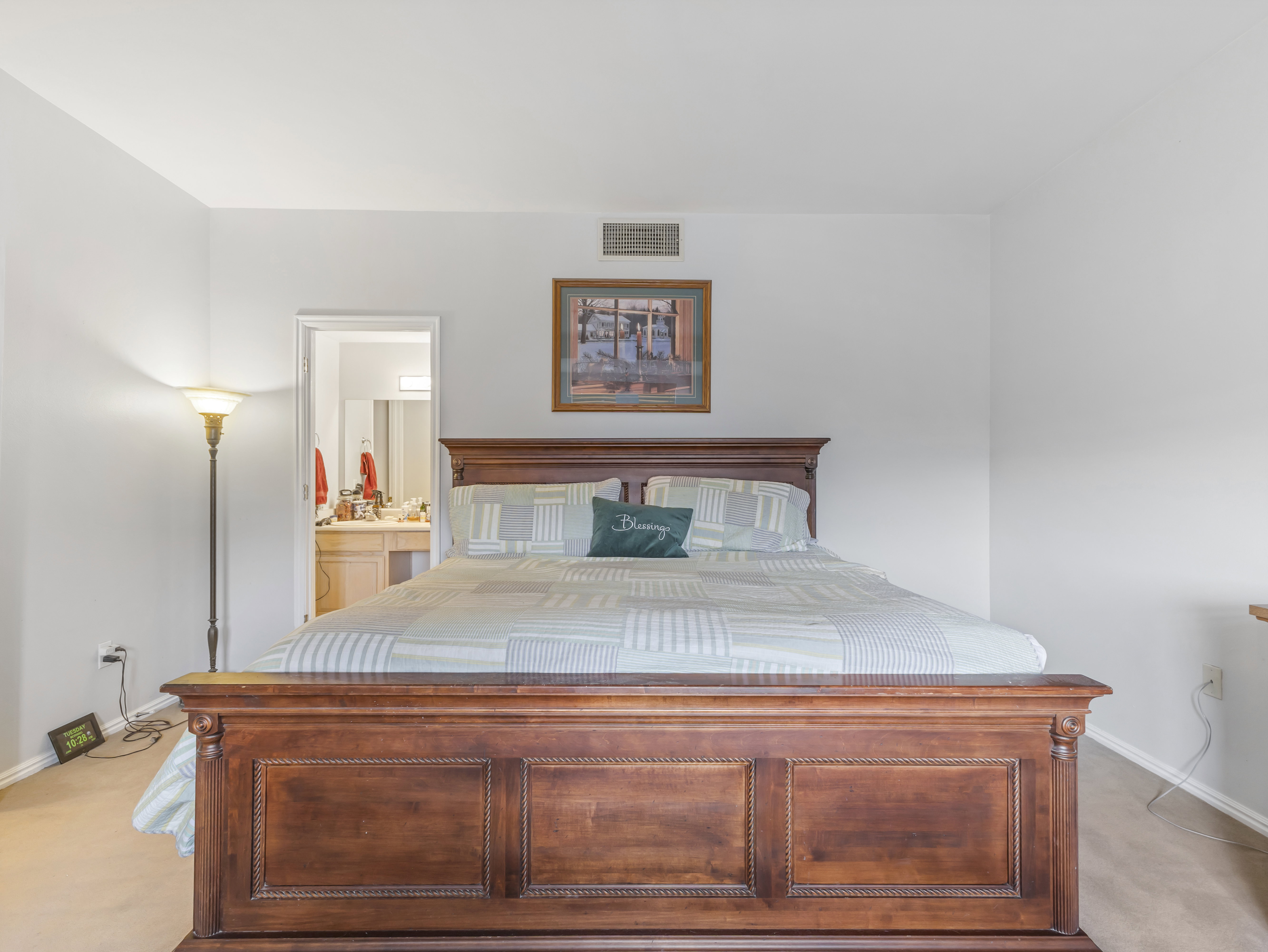 Bedroom featuring neutral wall paint, light-toned carpet, and a wood-finish bed frame