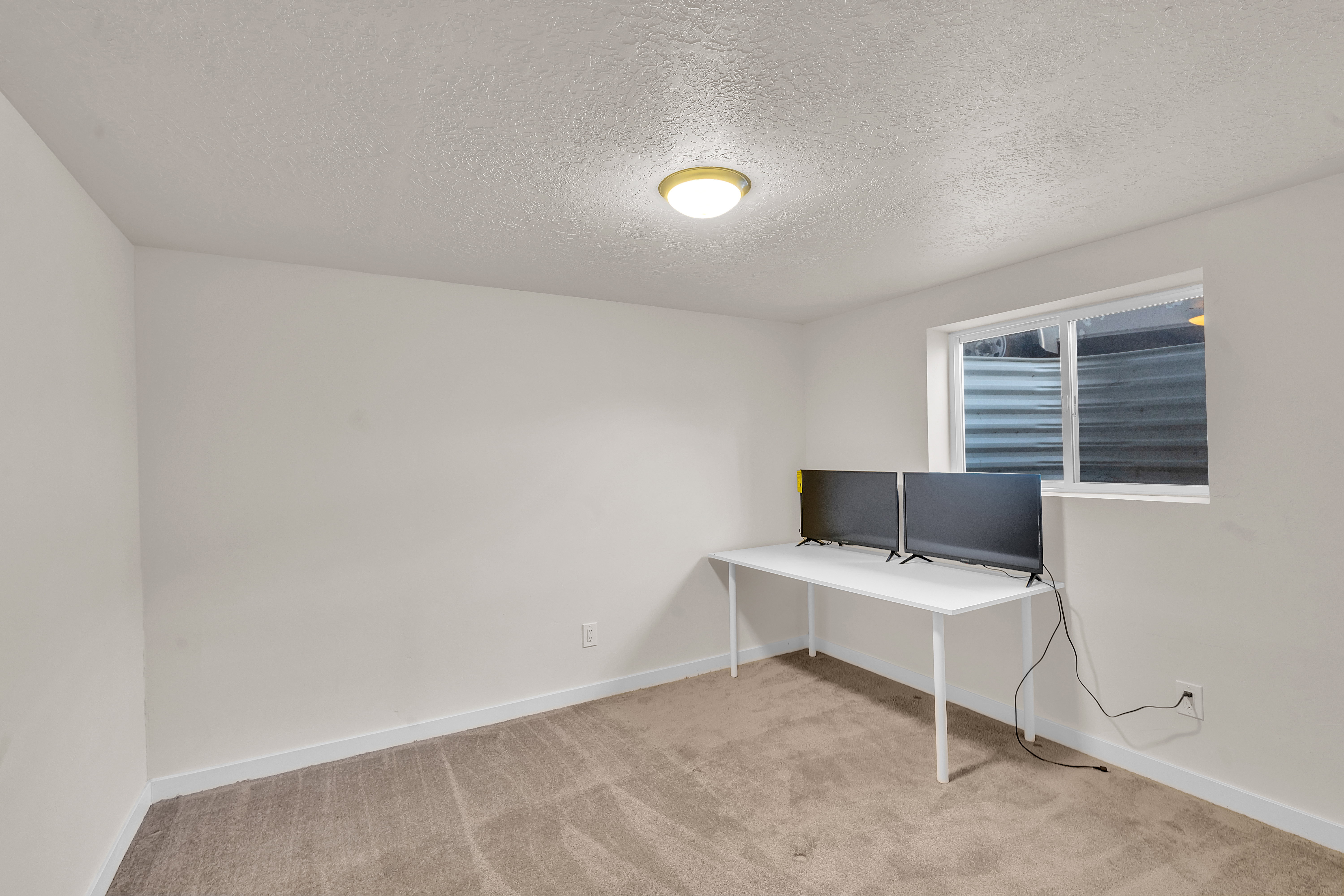 Carpeted room featuring a single window with a window well, white baseboards, and a flush mount ceiling light