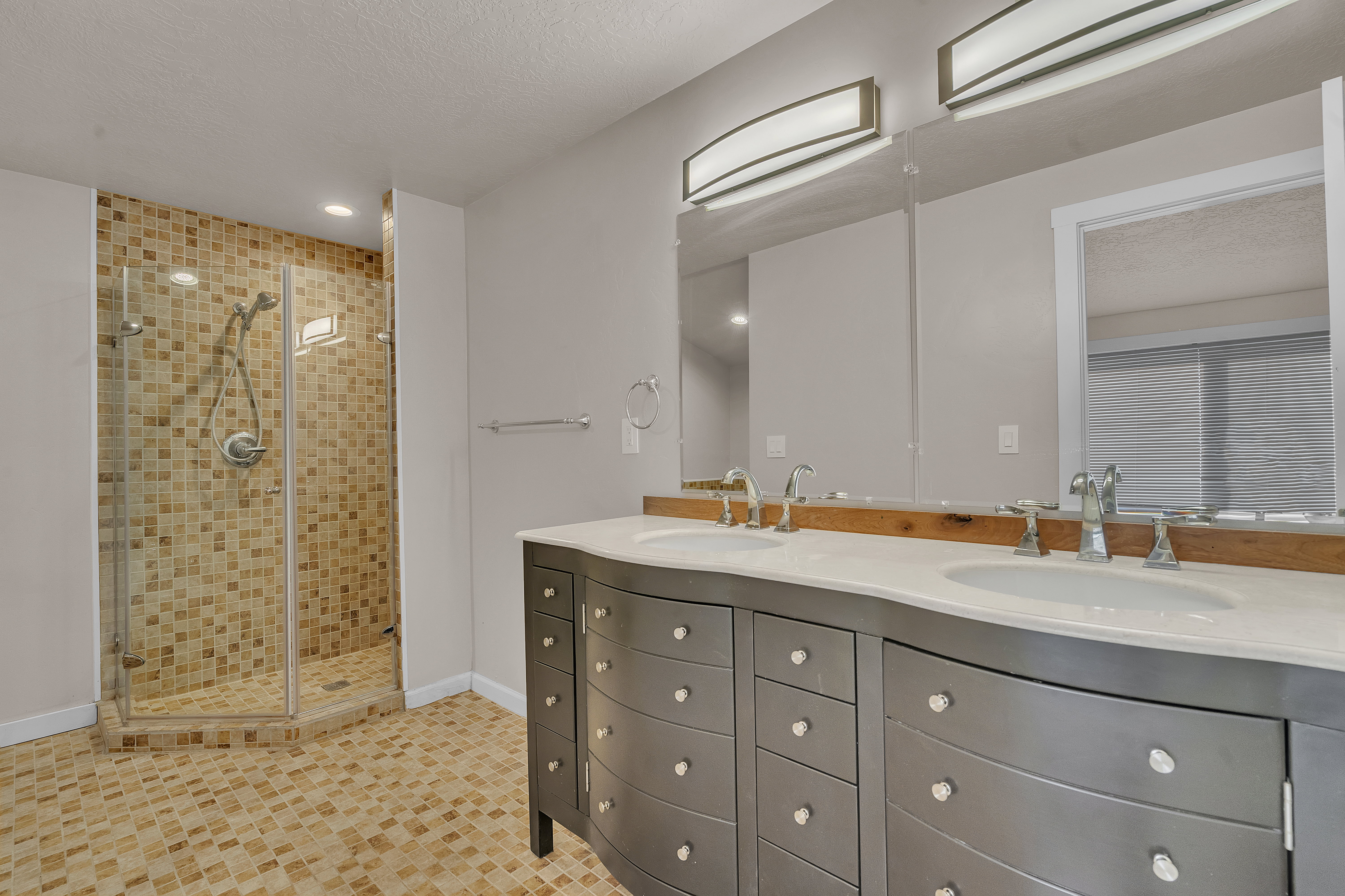 Bathroom featuring a dual vanity with undermount sinks and a glass-enclosed shower