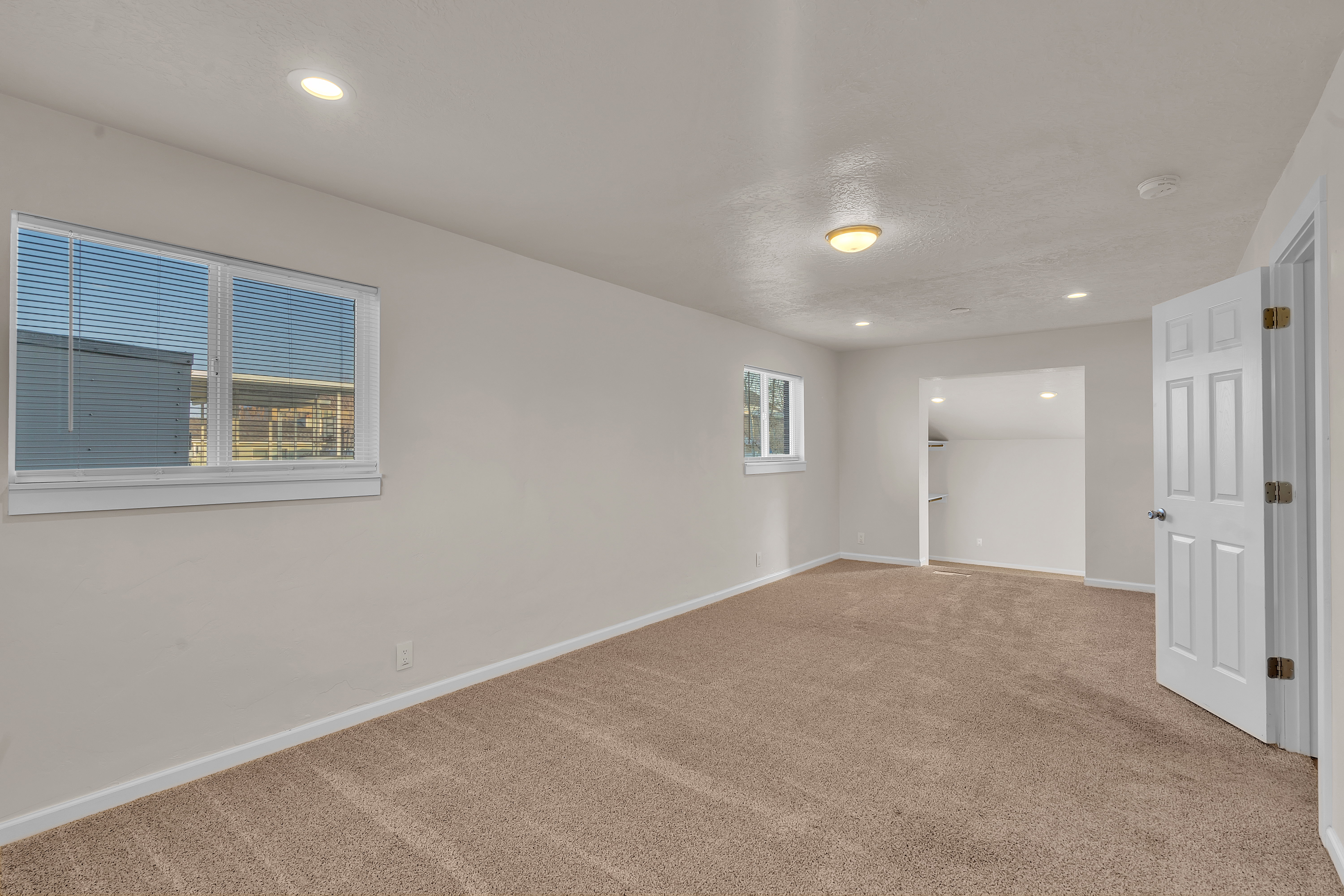 Carpeted interior space featuring neutral wall paint, recessed lighting, and a six-panel interior door