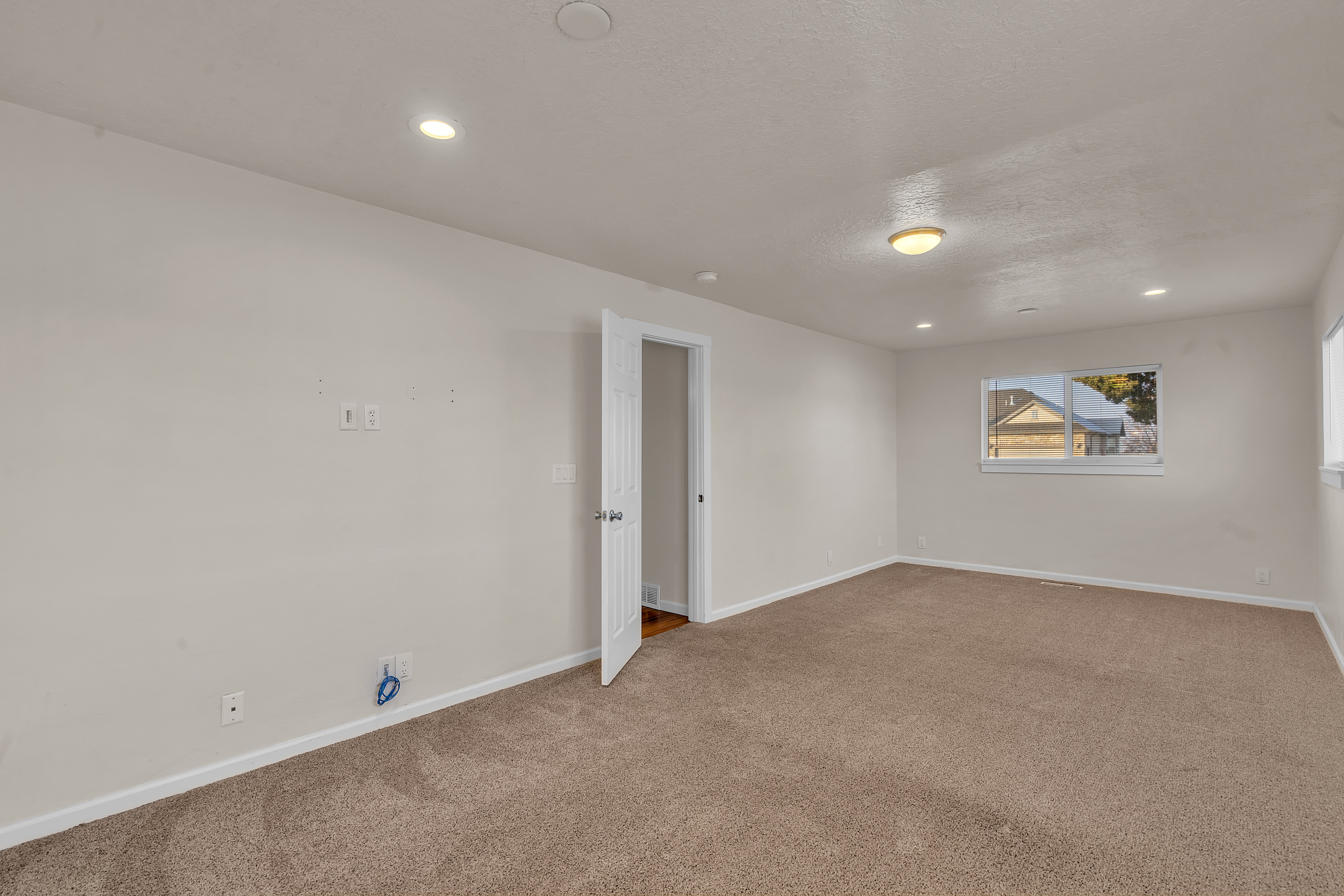 Carpeted interior space featuring white baseboards, a white door, and white walls