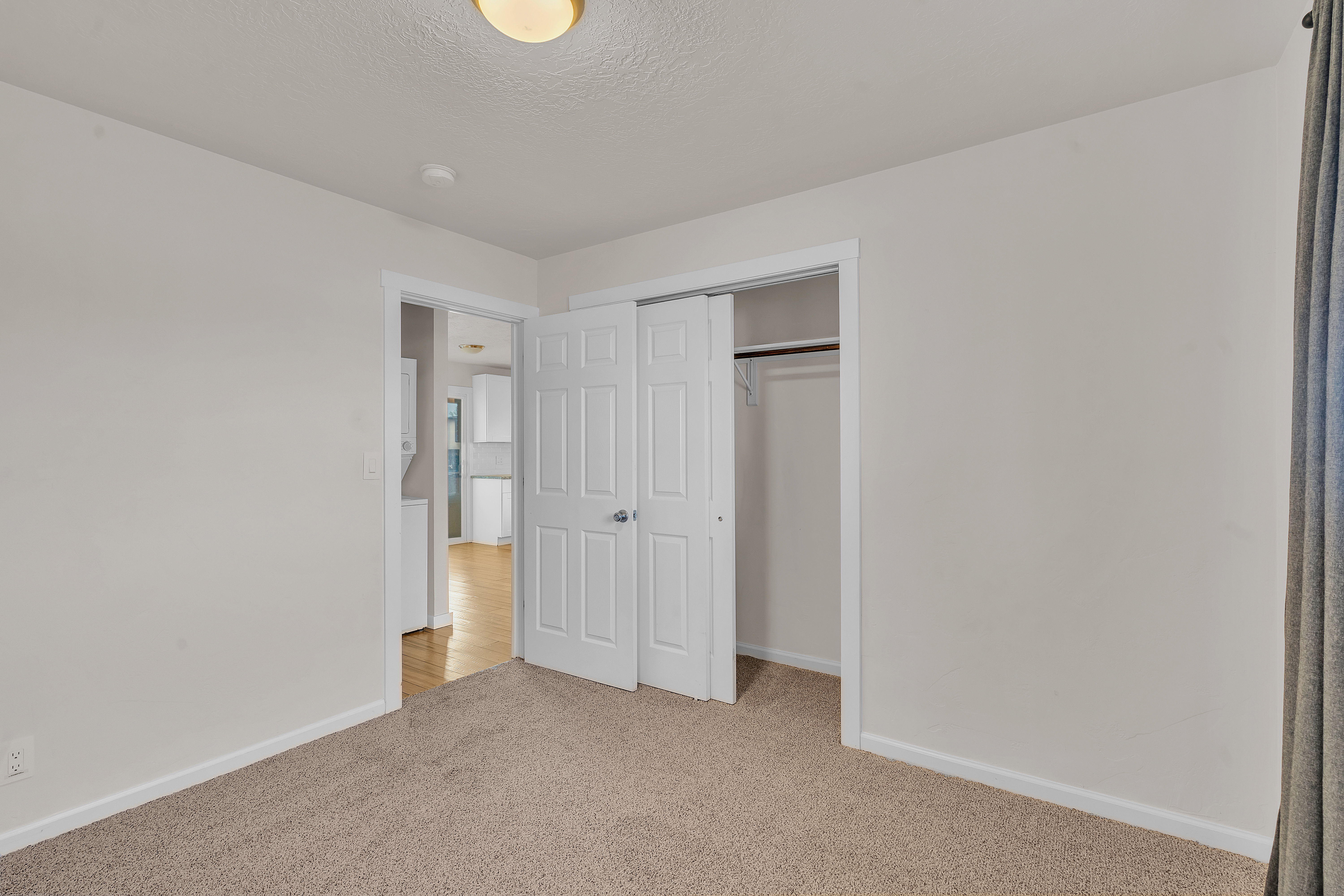 Carpeted room featuring a double-door closet with a hanging rod, neutral wall paint, and a semi-flush mount ceiling light