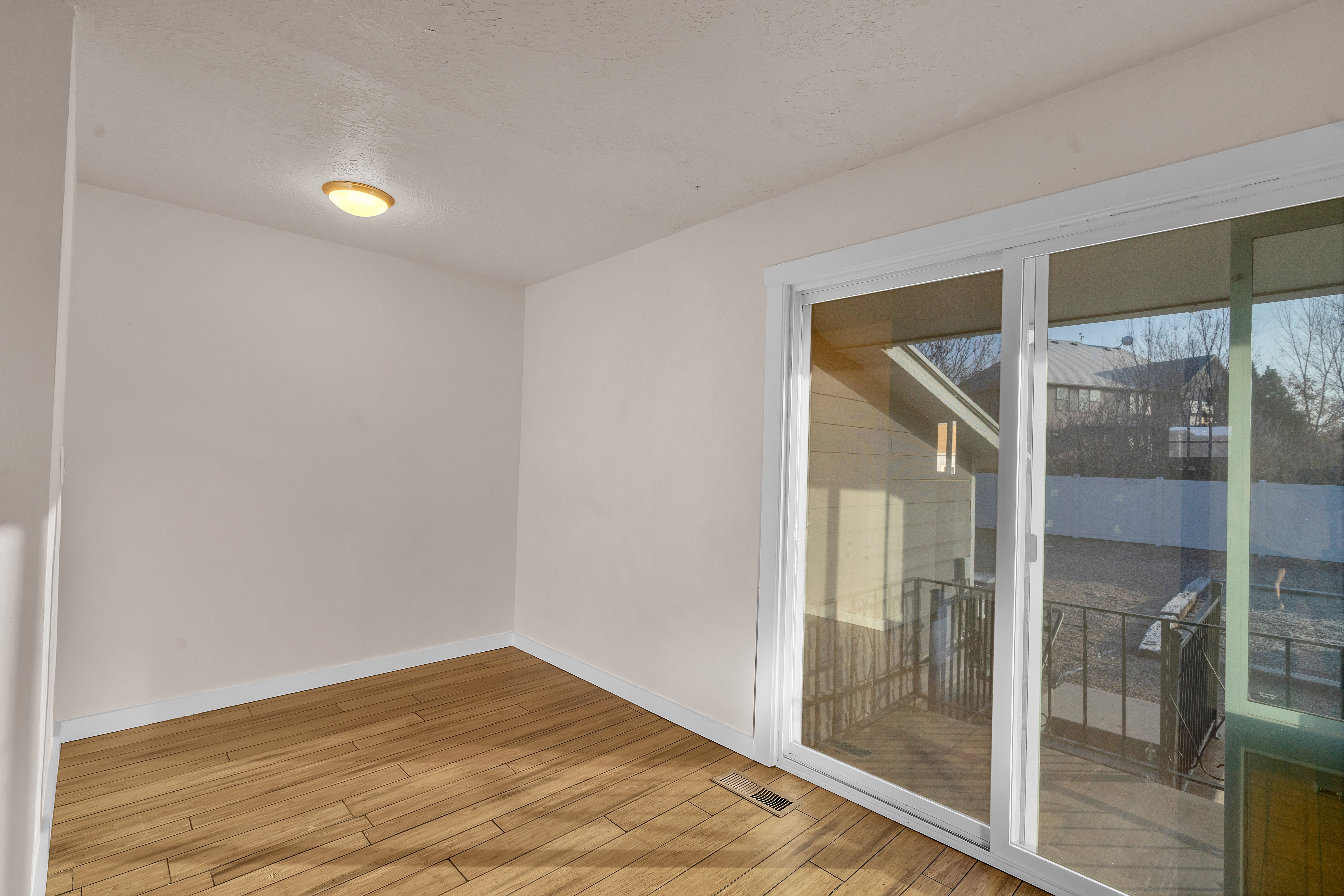 Room featuring wood-finish flooring, white walls, a flush-mount ceiling light, and a sliding glass door providing exterior access